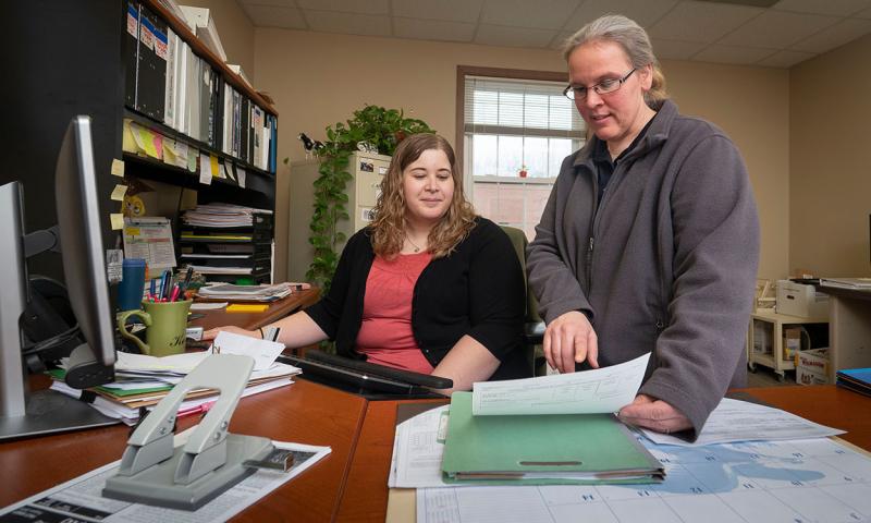 Two producers reviewing financial paperwork in a farm office.