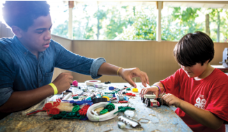 Two young boys at a table constructing a robot.