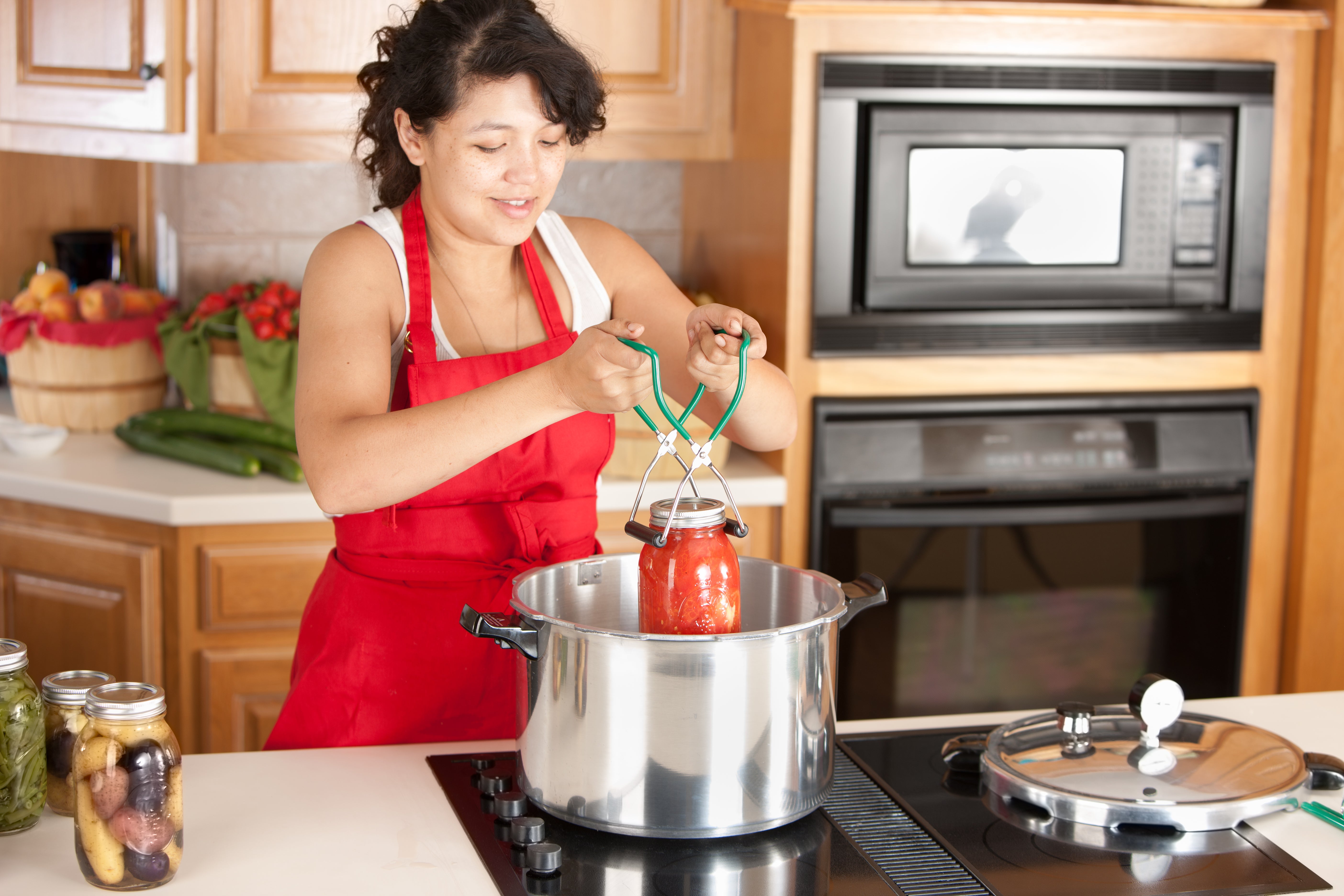 woman canning tomato products in her kitchen