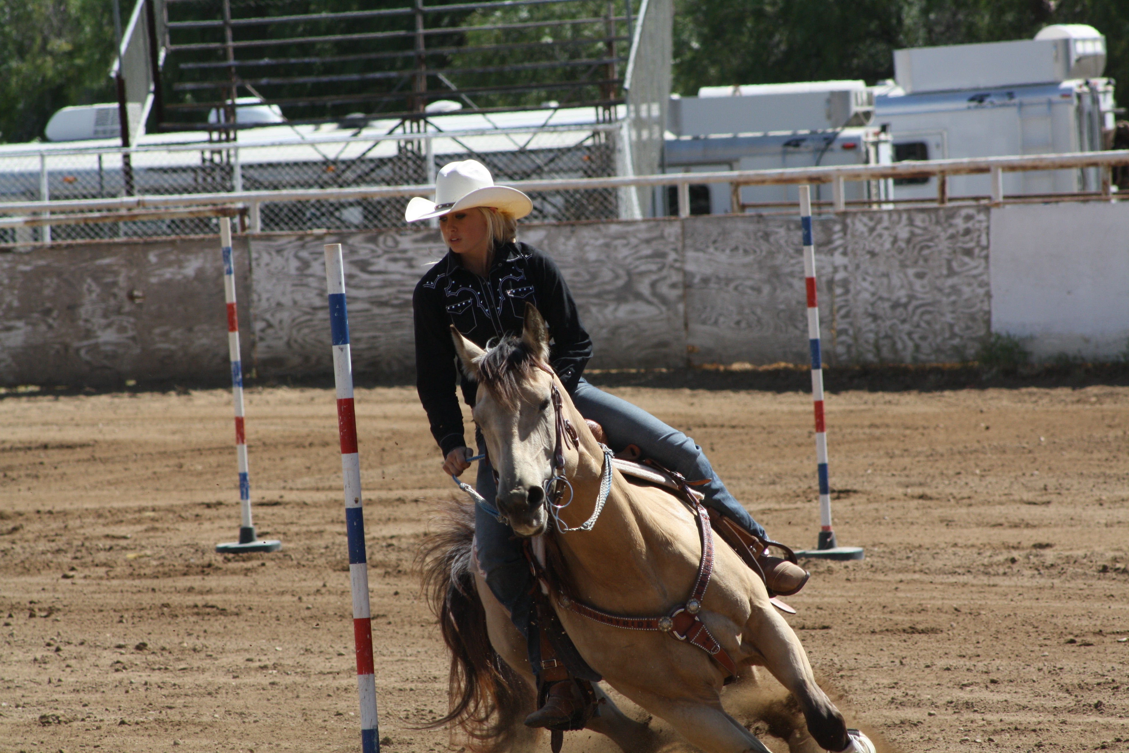 young cowgirl running a horse through the pole bending pattern