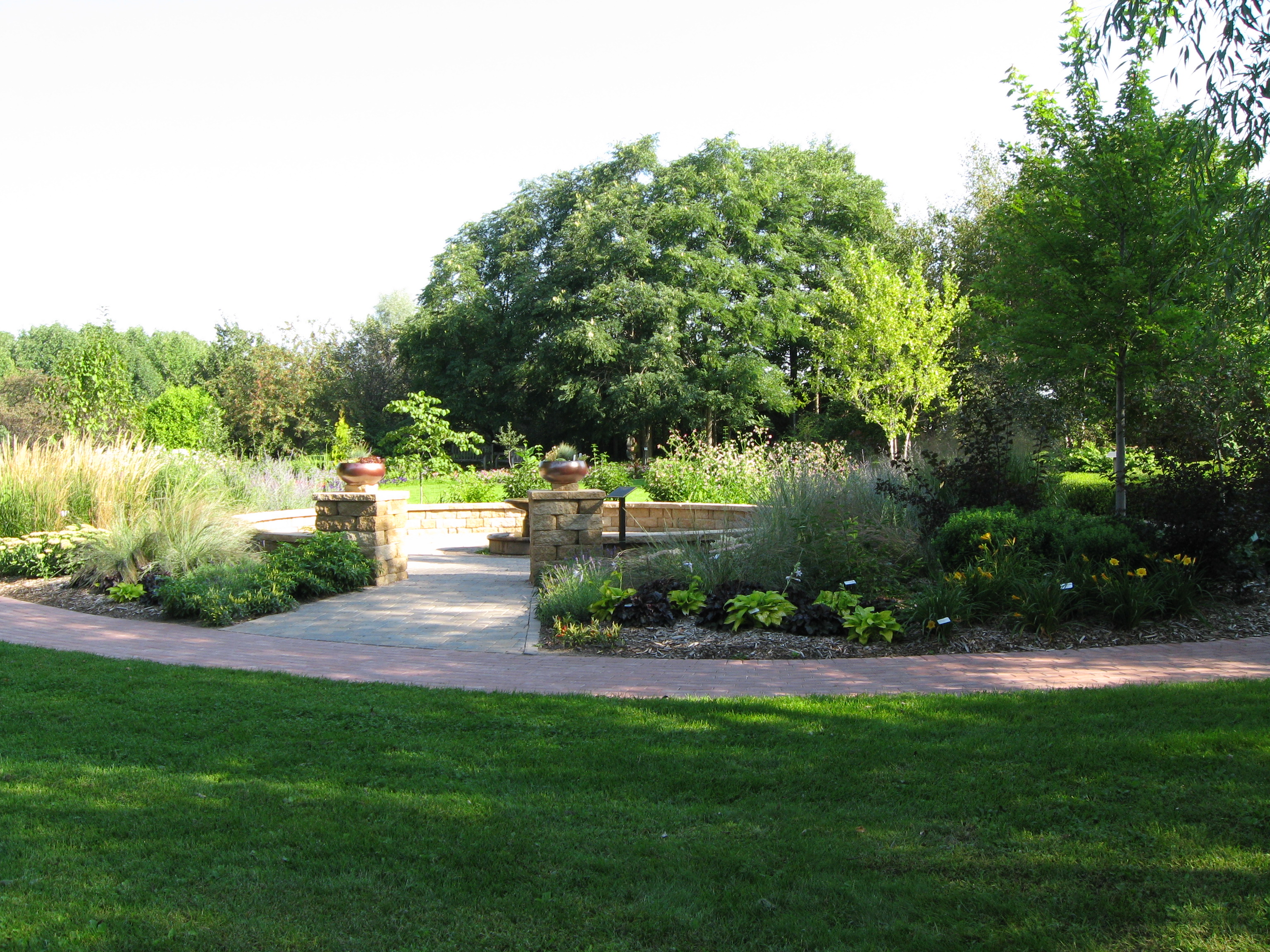 A lush, landscaped garden with a walkway and a variety of herbaceous plants.