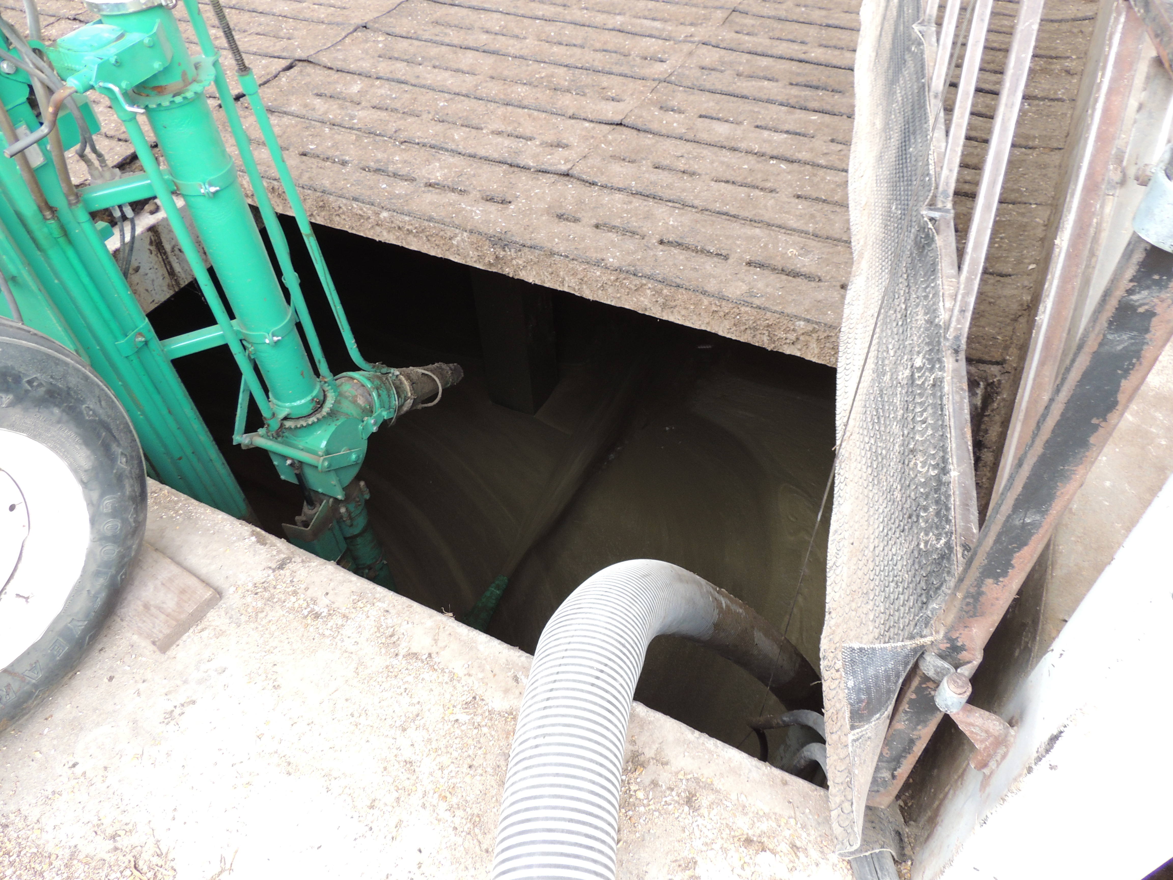 A slatted floor with an open area. A hose is running into the open area.