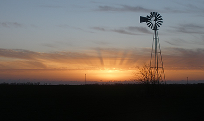 a windmill in front of a sunset
