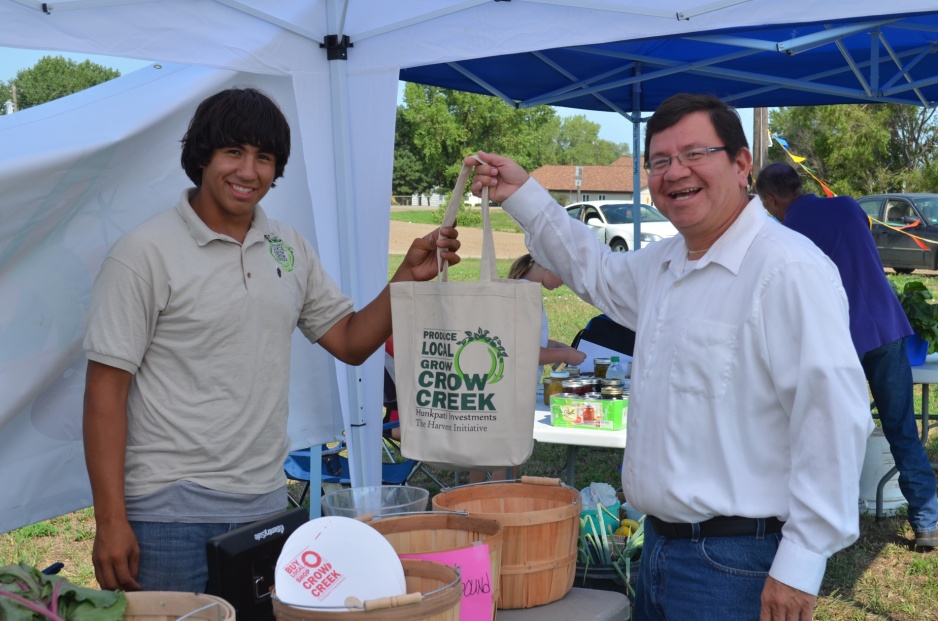 A young native american man handing a customer a canvas bag.