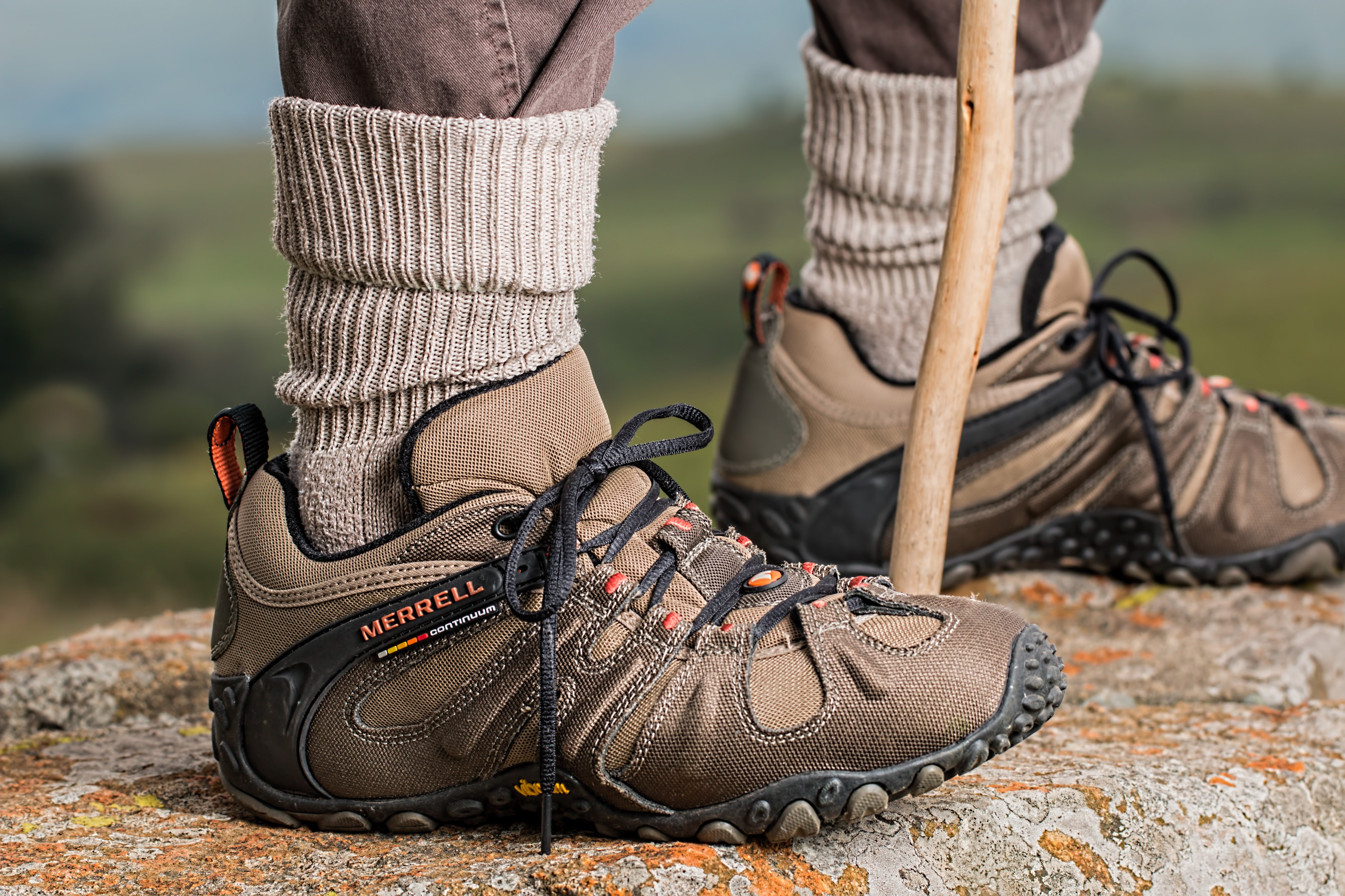 An older man wearing hiking boots standing on a rock.