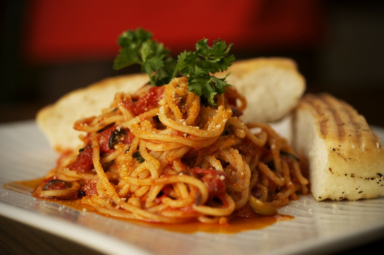 A plate of spaghetti with meat sauce and two slices of garlic bread.