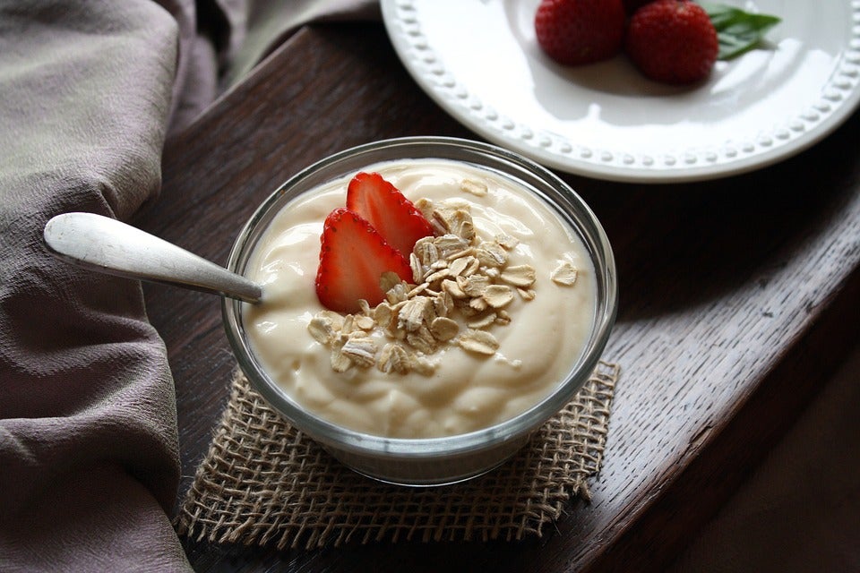 Fruit and yogurt in a glass with a spoon.