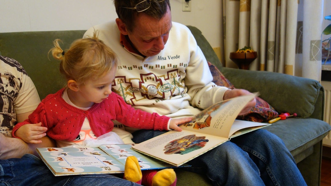 A father reading a book with his young daughter.