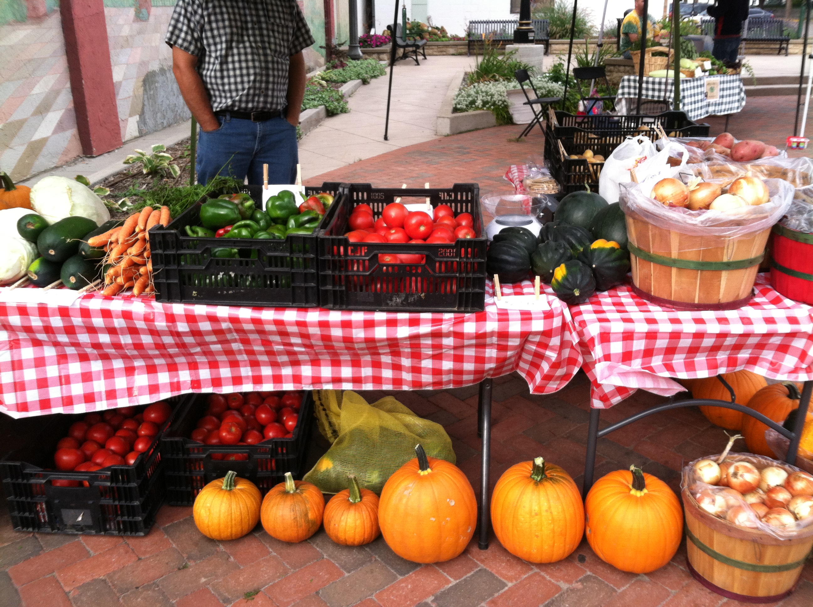 A table at a farmers market filled with fresh vegetable displays.