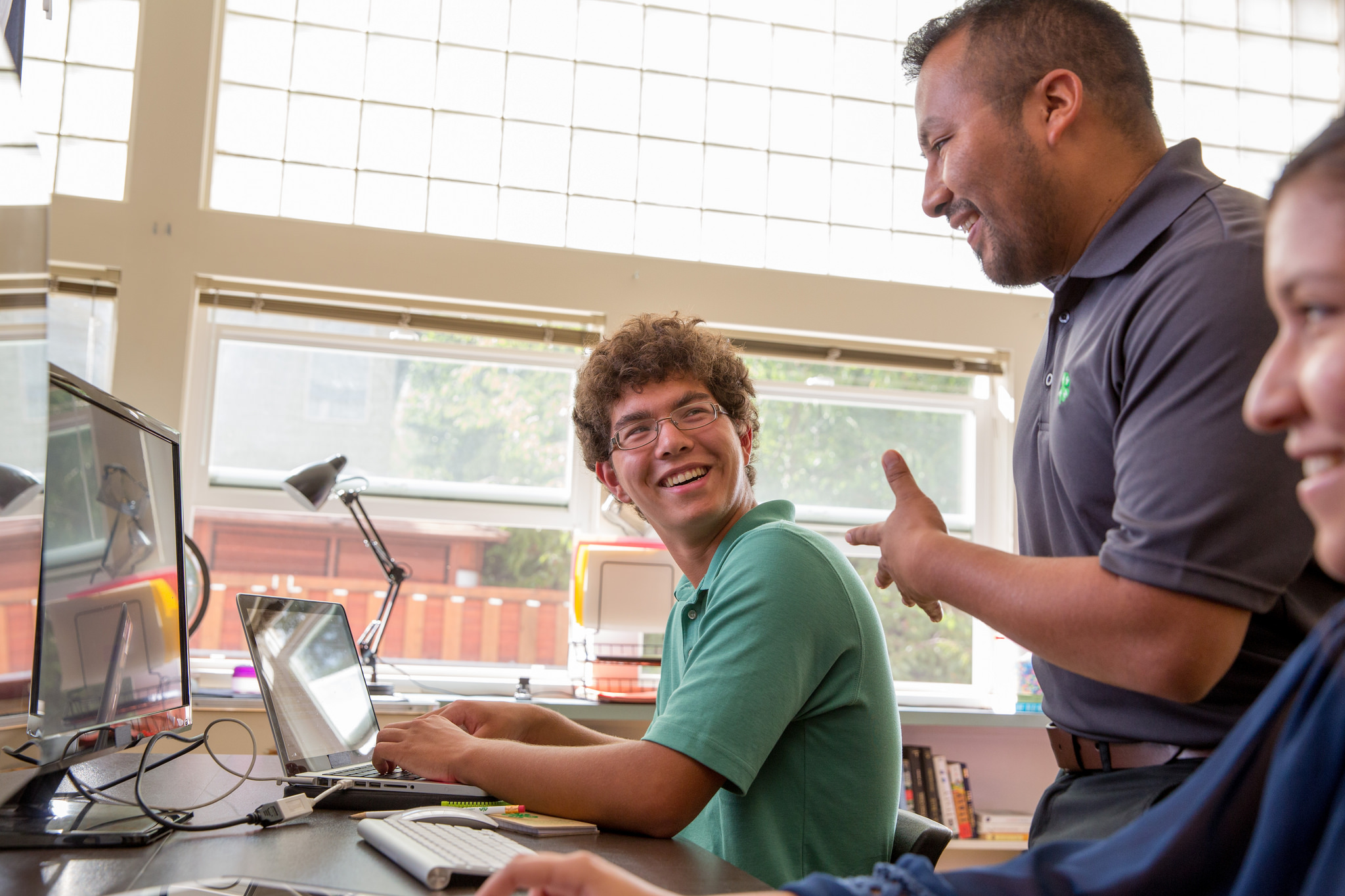 A young man sitting at a laptop discussing a project with a 4-H leader.