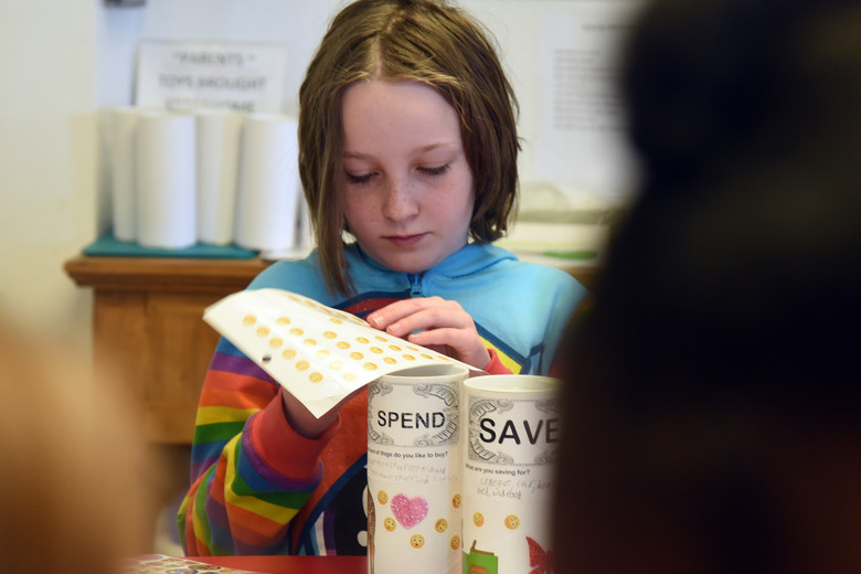 Young girl decorating two cans for saving and spending.