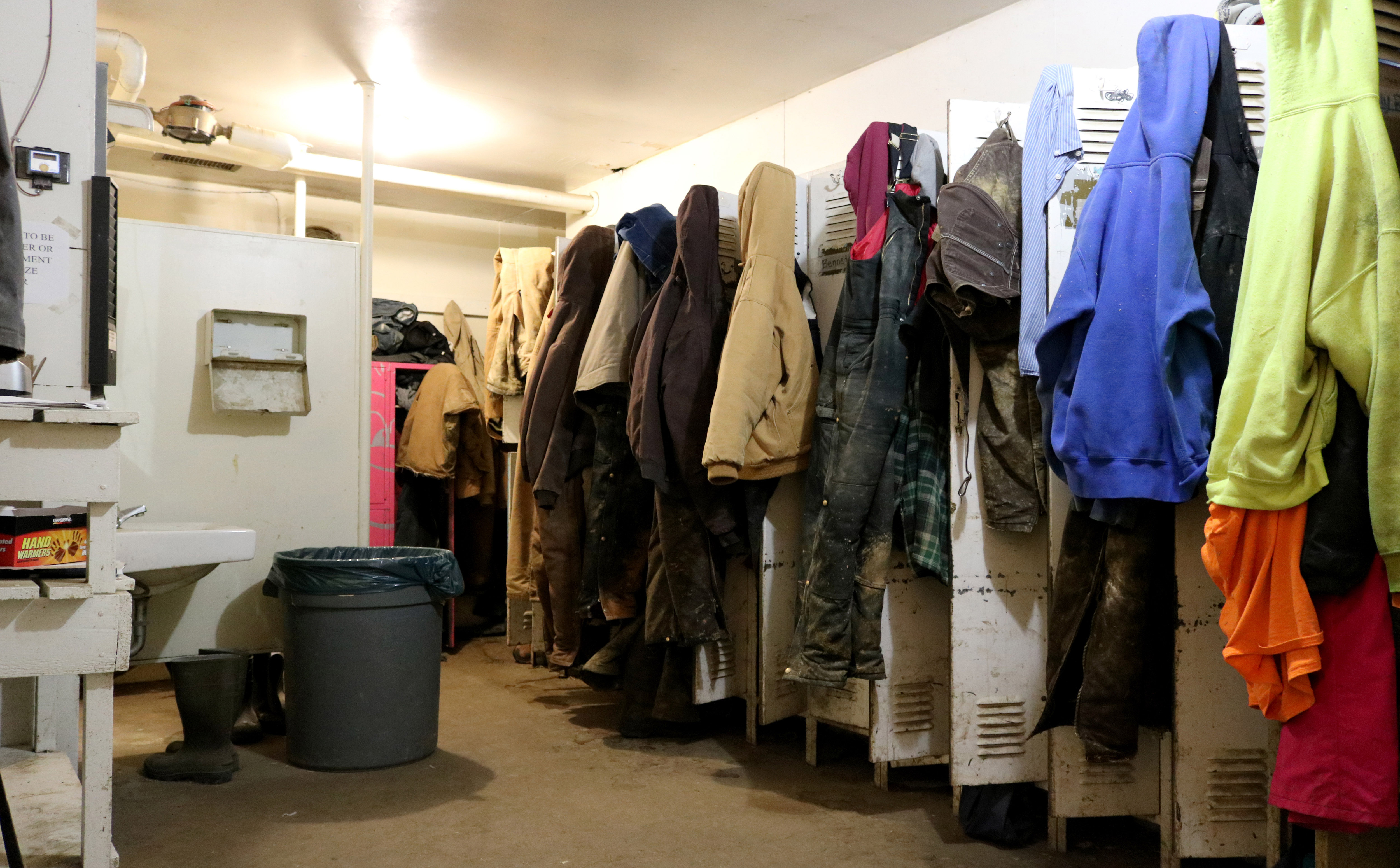 row of lockers with several employee jackets, hats, and clothing hanging outside.