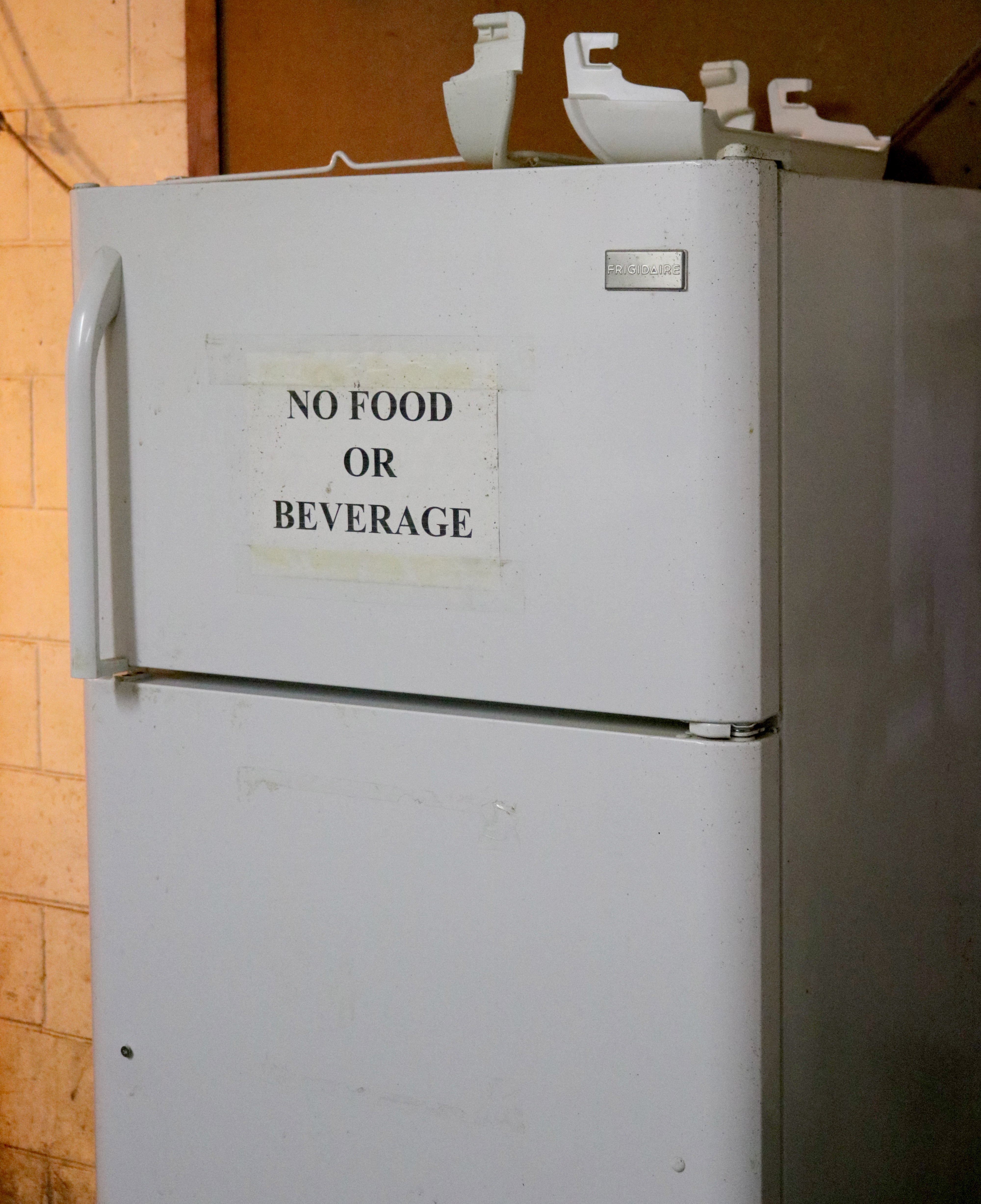 refigerator with "No Food or Beverage" sign taped on the outside.