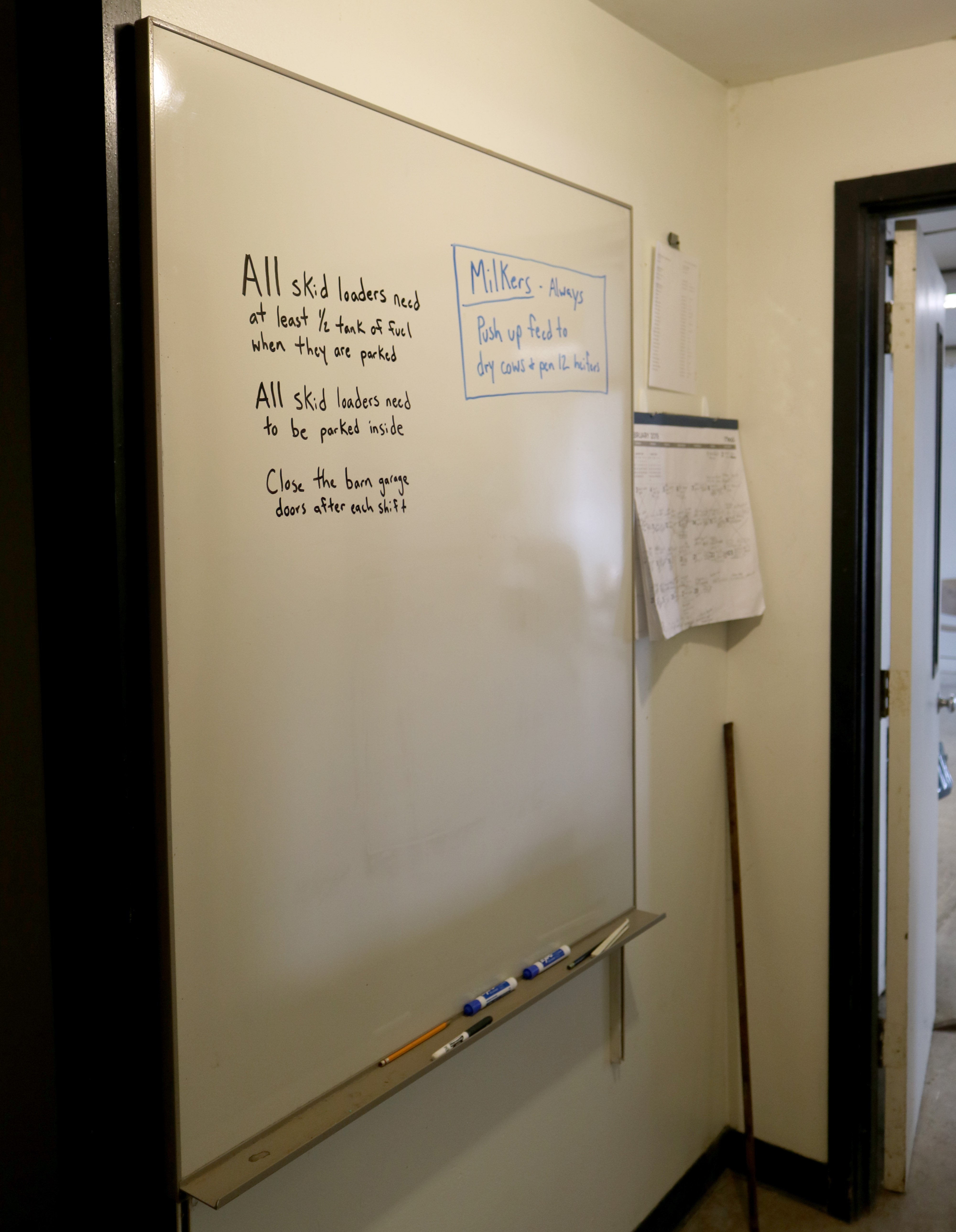 white board mounted on wall with instructions written on it in black and blue marker