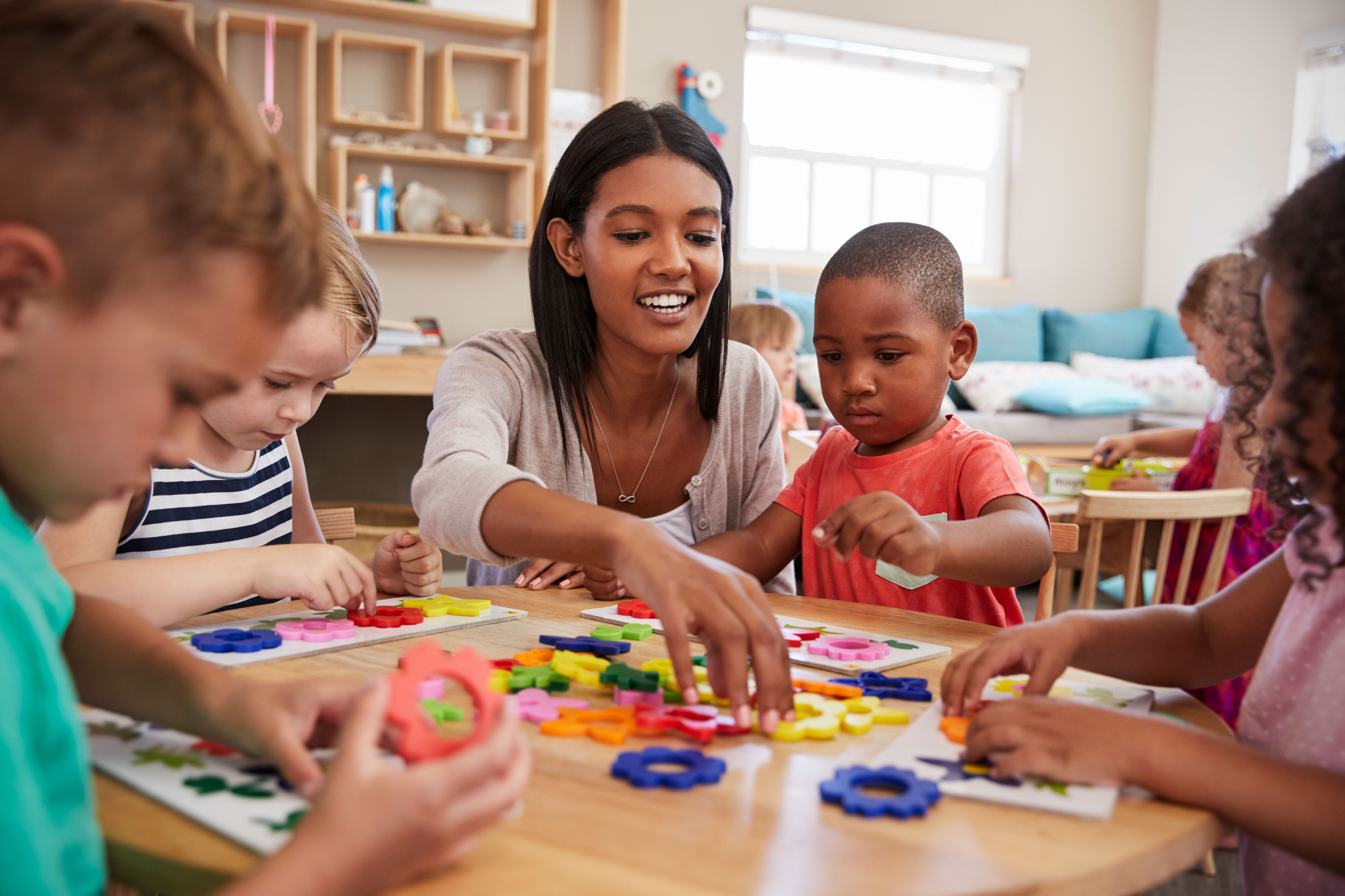 a young woman leading a group of young children in a learning activity