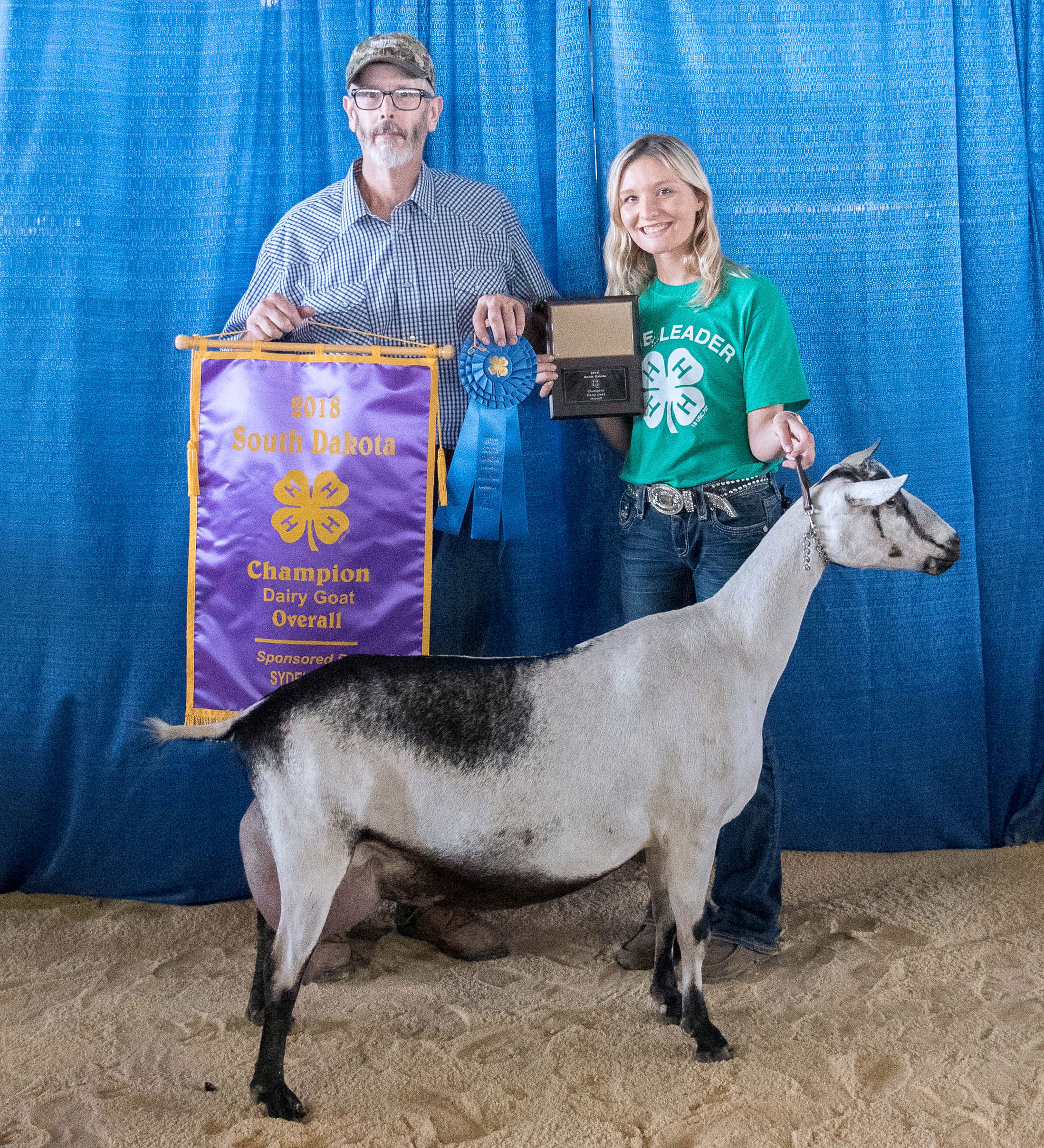 father and daughter holding numerous 4-H awards with their dairy goat