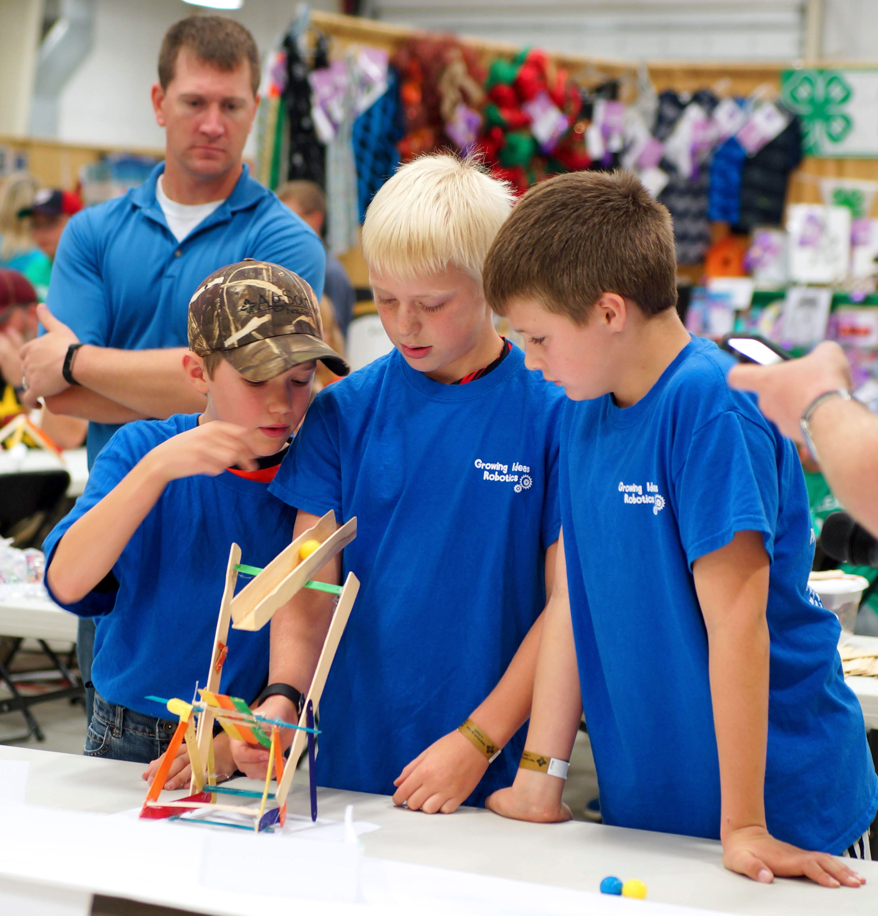three male 4-H youth inspecting a catapult that they built