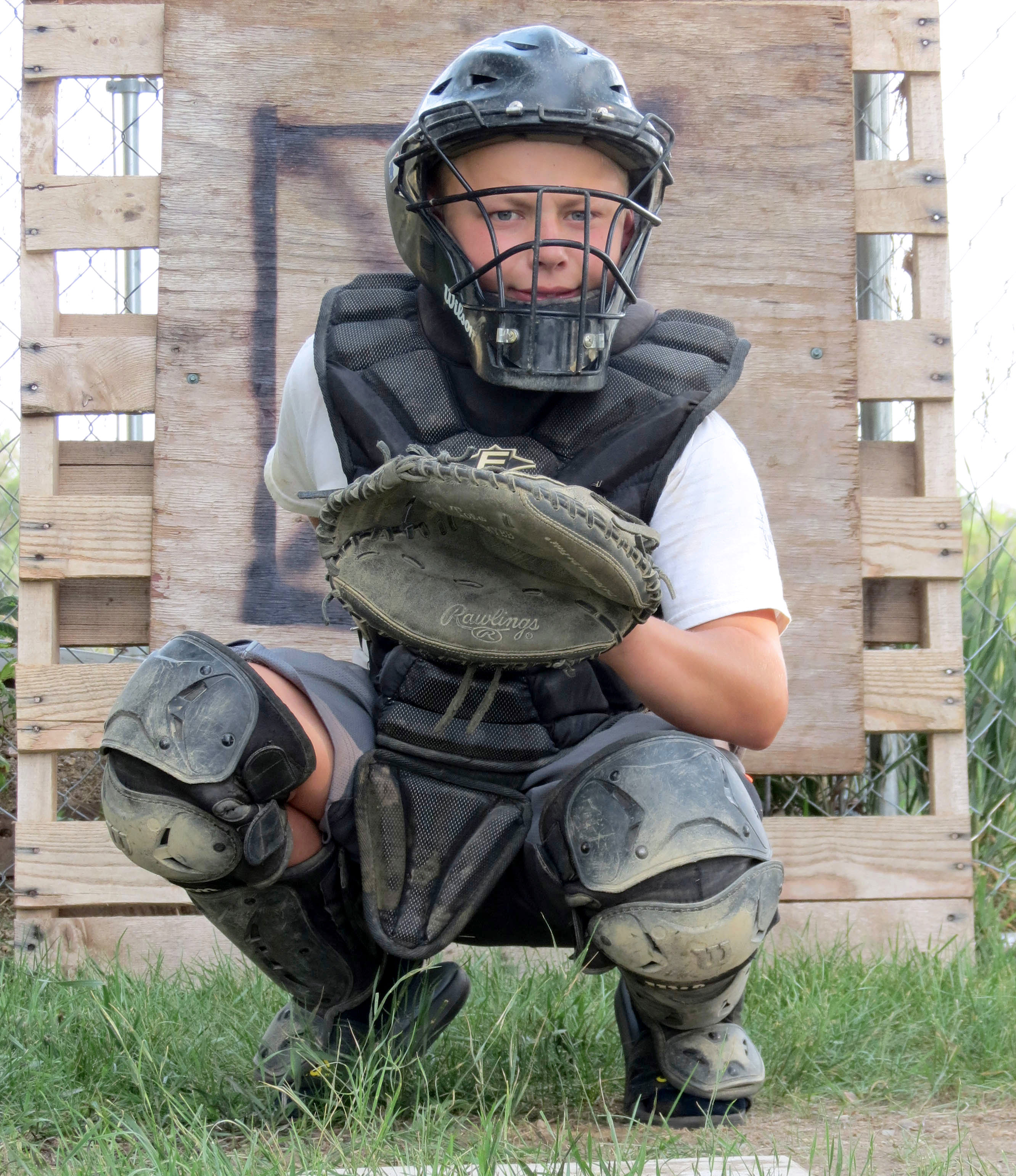 male youth dressed in baseball catcher's equipment