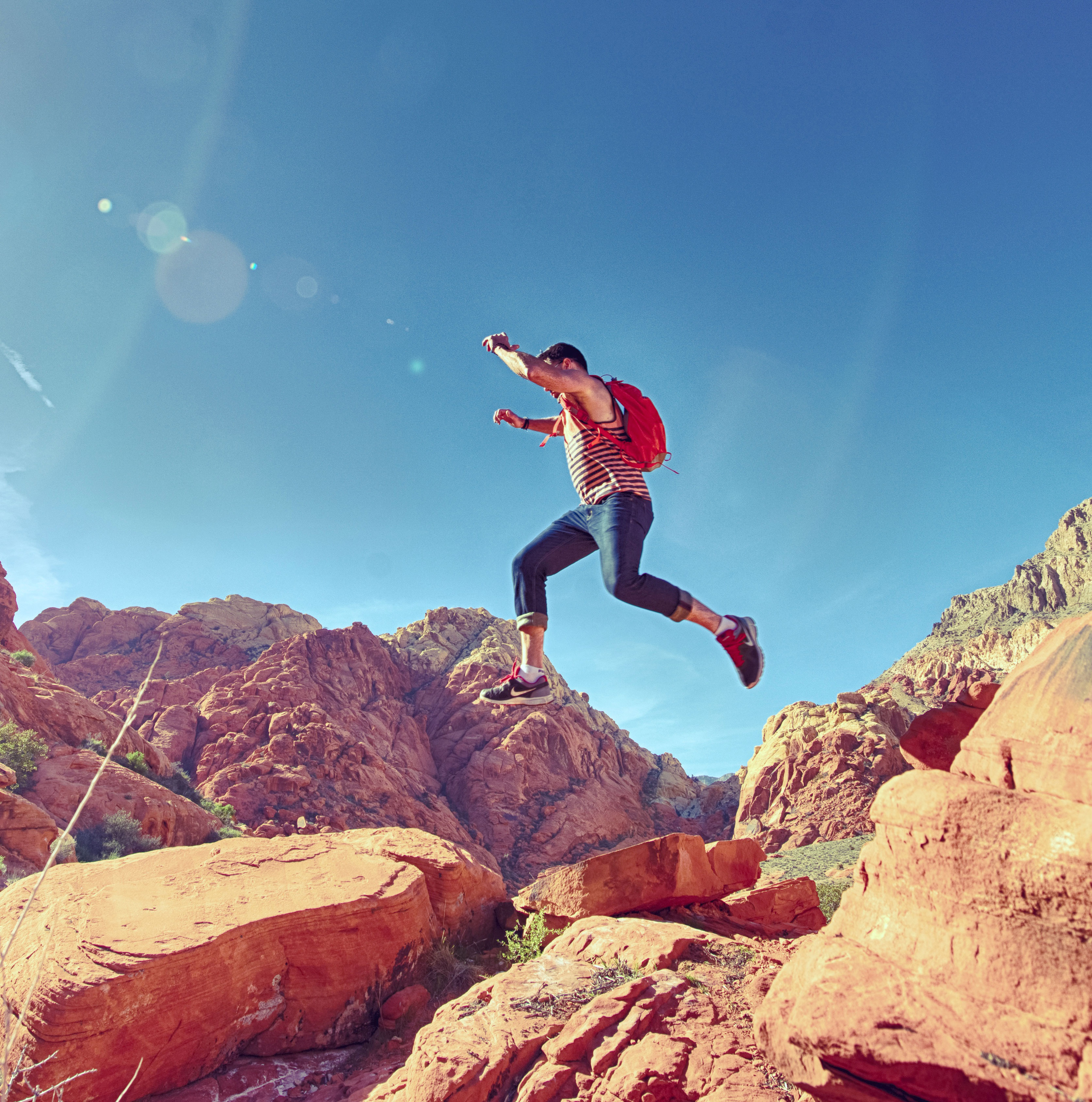 male youth bounding over desert rock formations