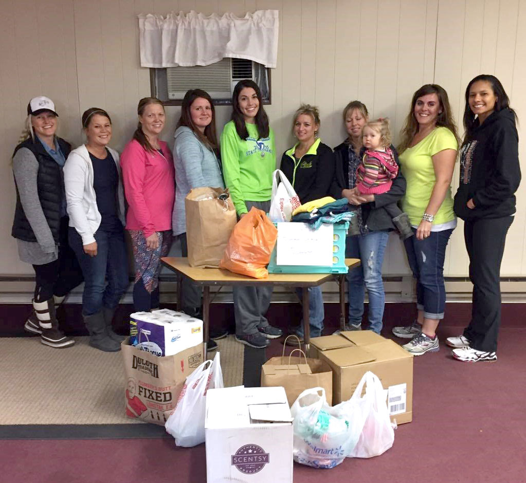 group of young women standing by a table of donated items