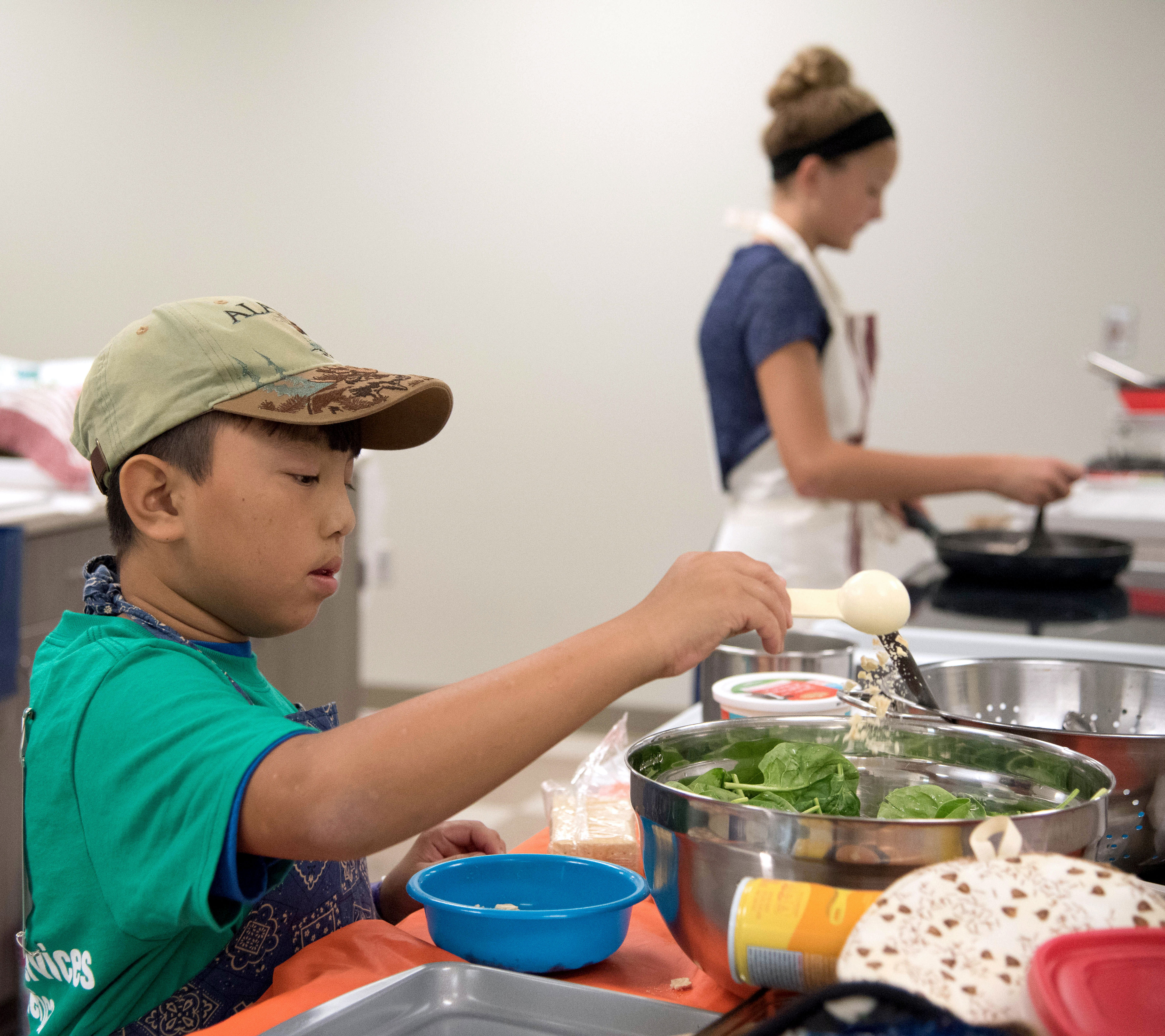 male 4-H youth preparing a salad in a silver mixing bowl