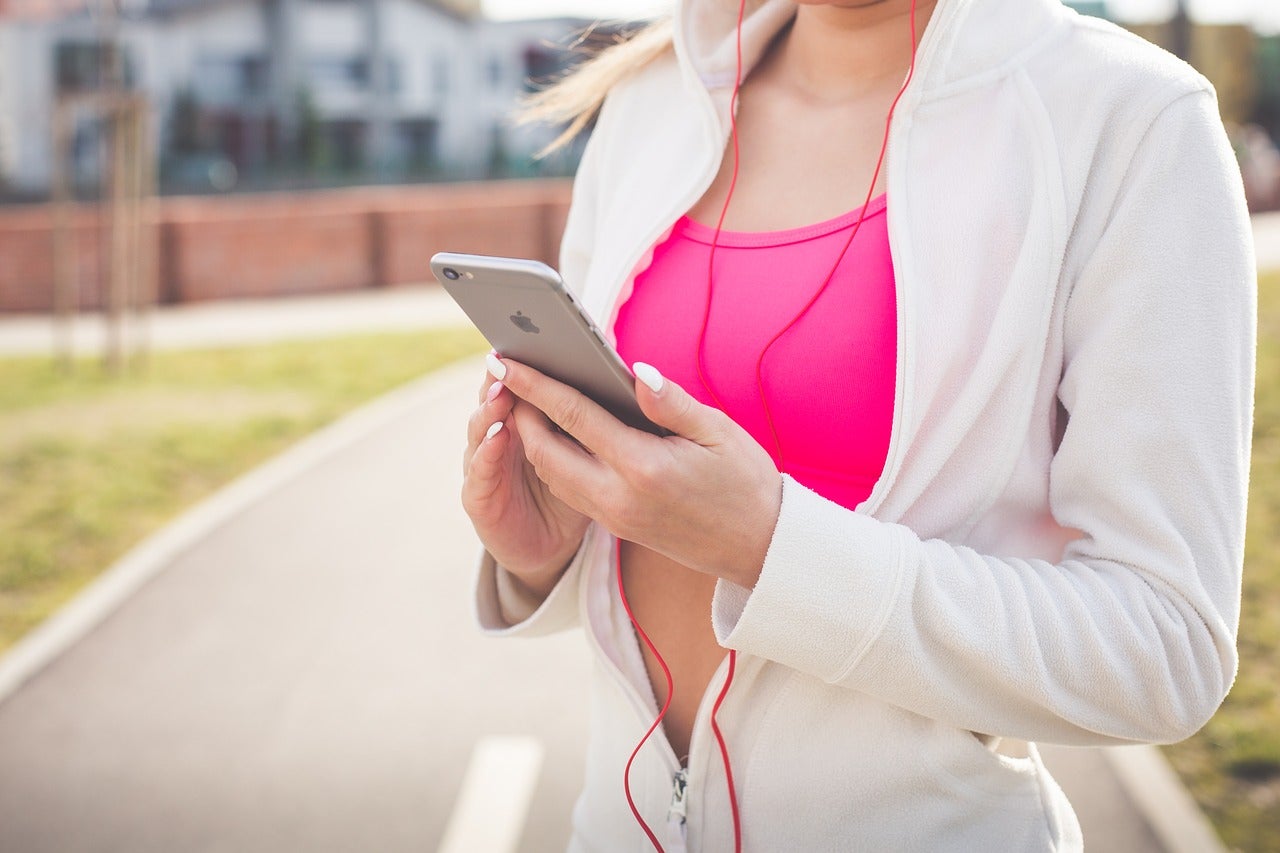 young woman in jogging outfit reading information on her phone