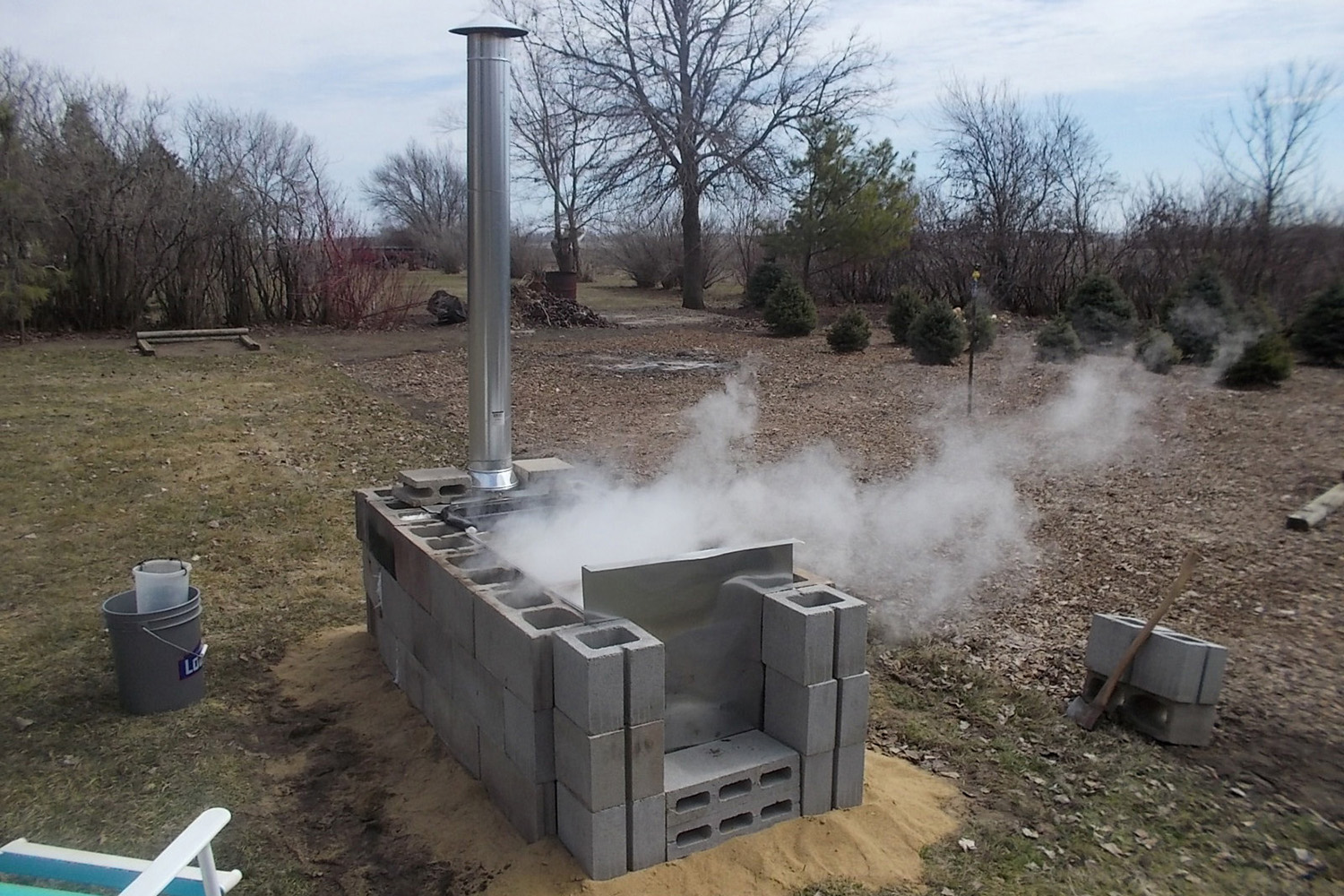 a home evaporator made of cinder blocks with a tall silver chimney