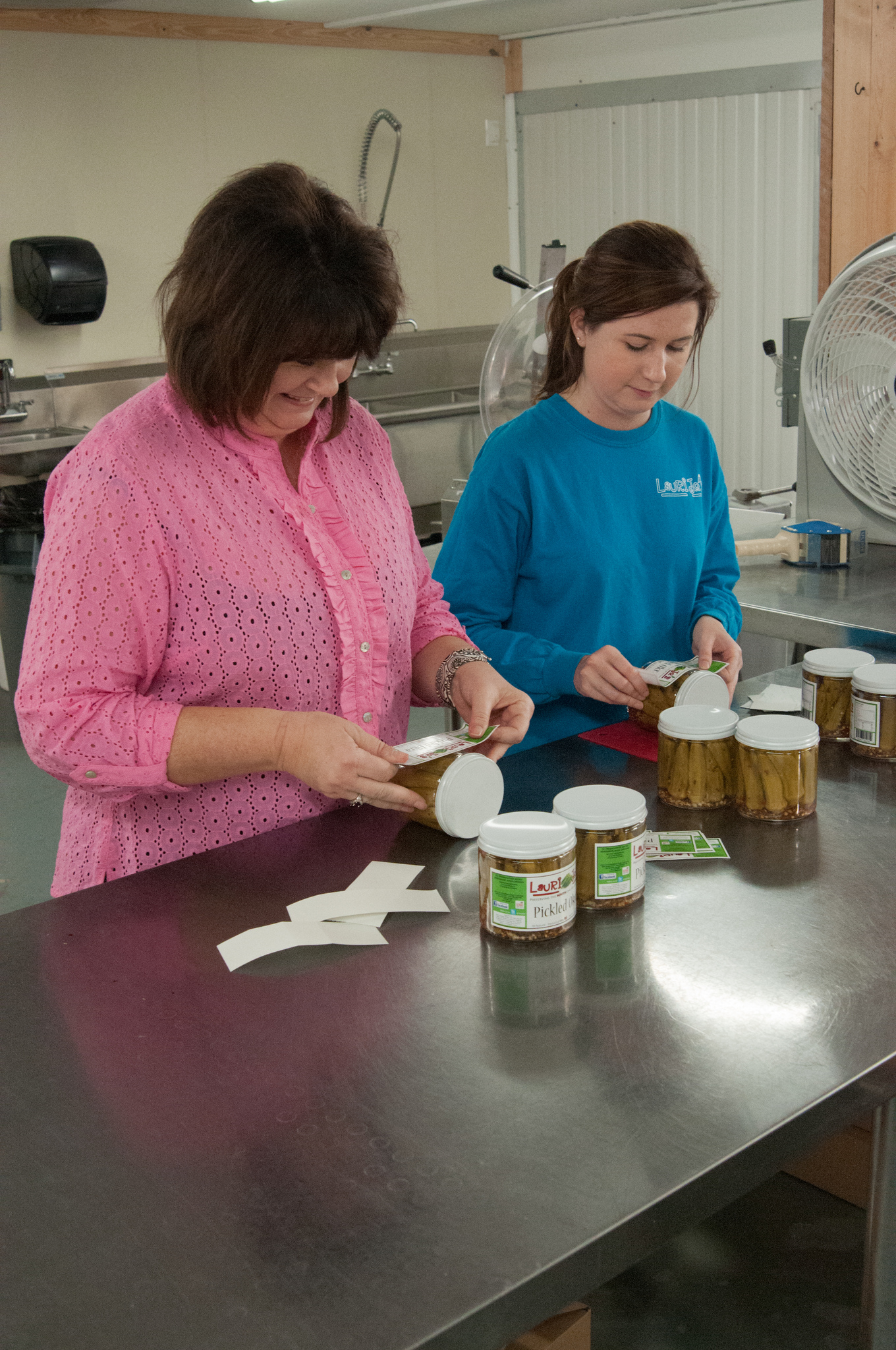a mother and daughter putting labels on home-canned food products. Photo by Stephen Ausmus, USDA