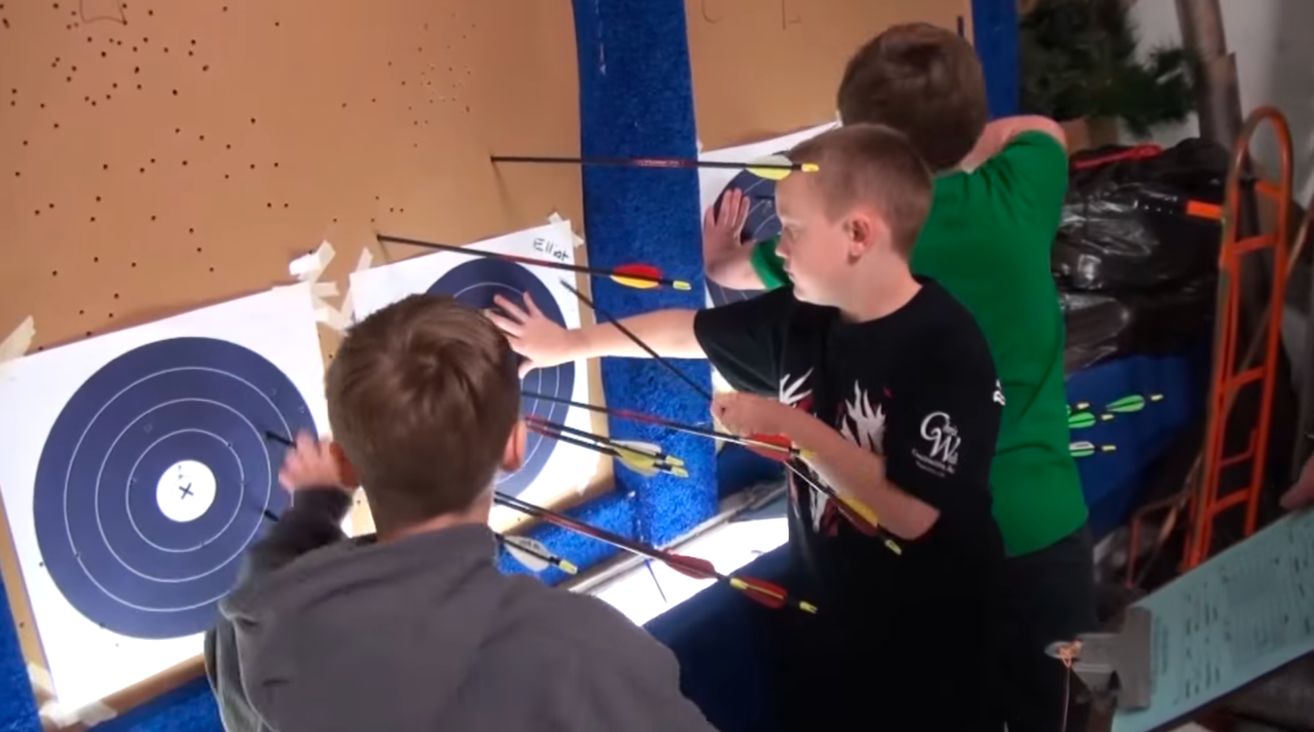 three male 4-H youth retrieving arrows from archery targets