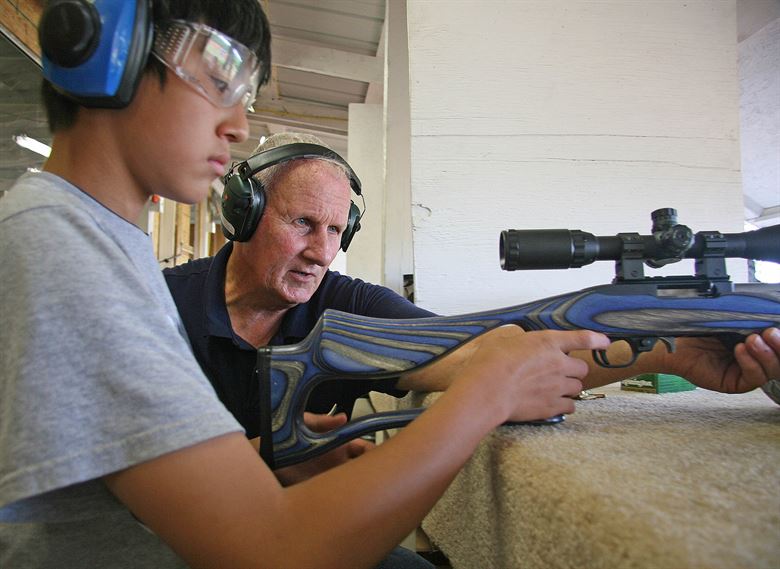 4-H youth with shooting instructor preparing to fire a rifle