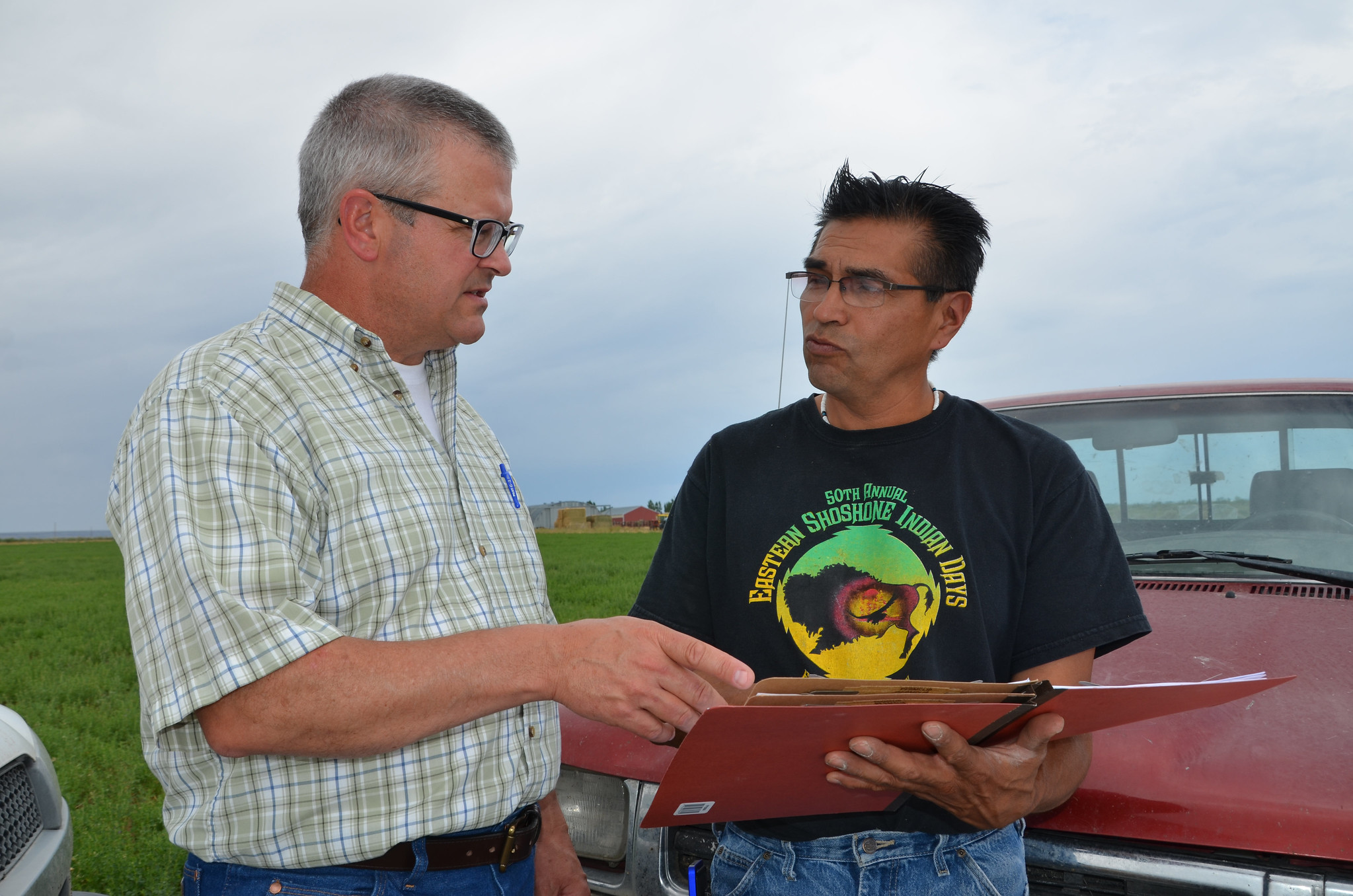 a livestock business owner reviewing a folder with his employee. Courtesy: USDA