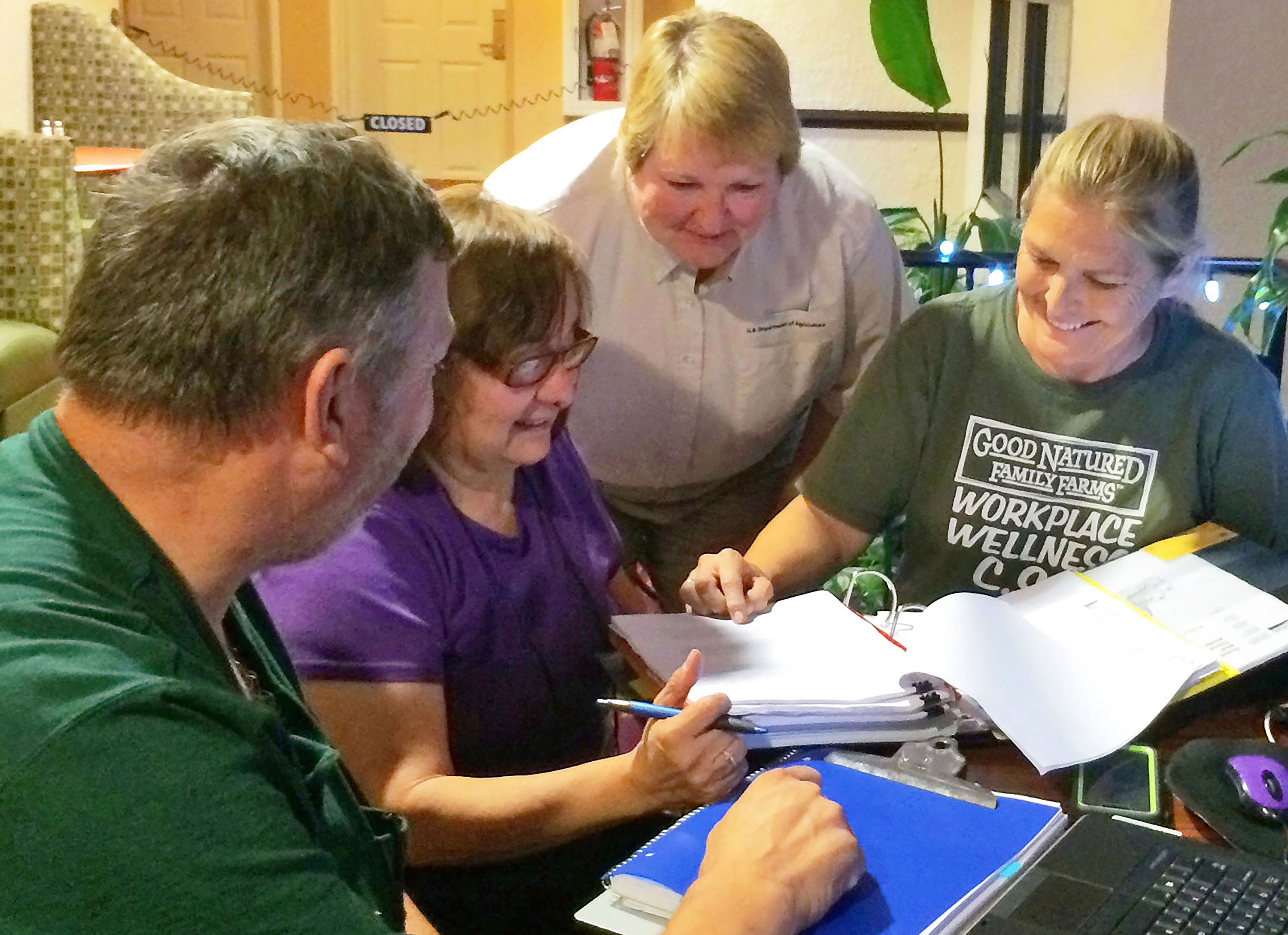 A male with three female farm administrators reviewing a binder of financial records. Courtesy: USDA