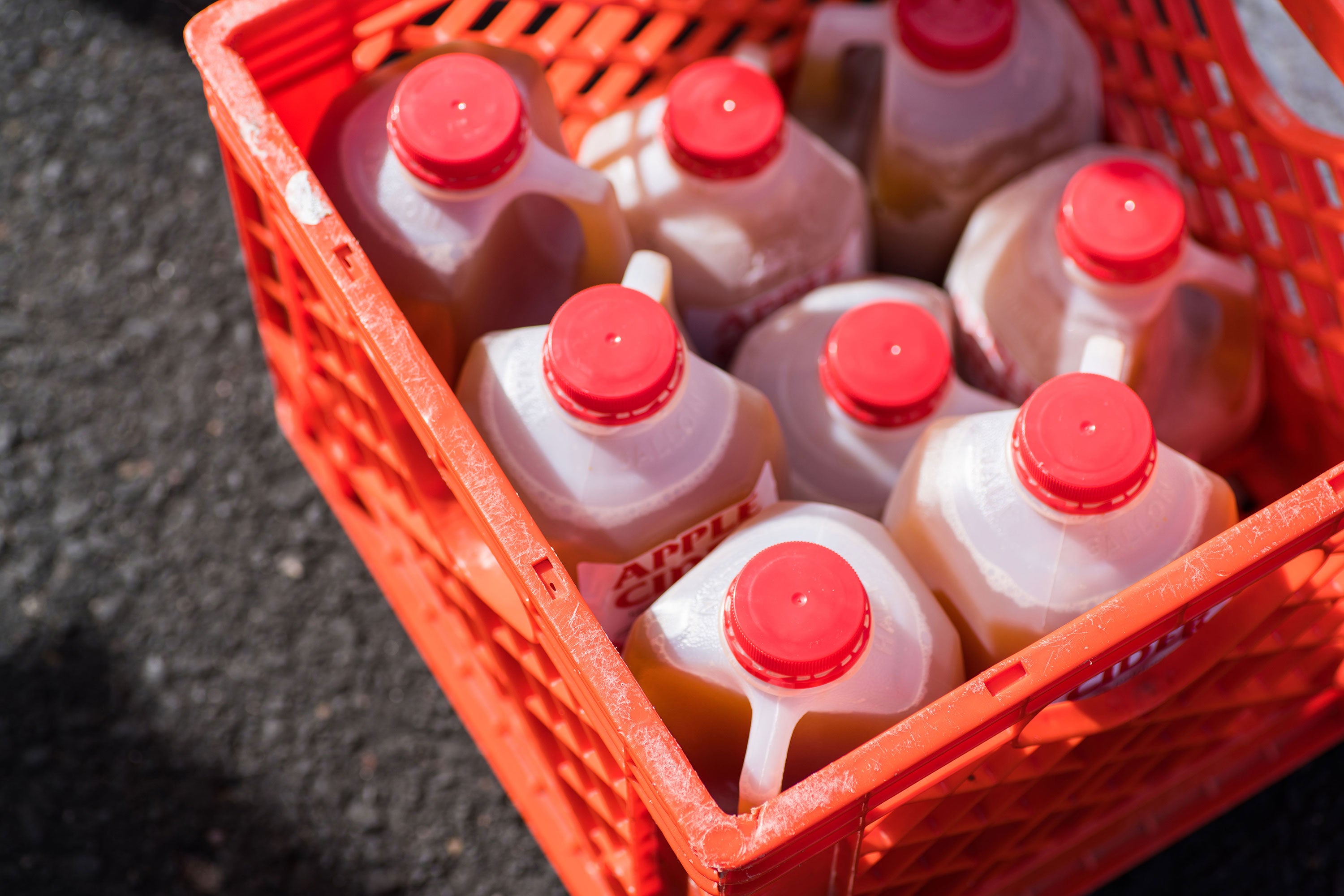 Several sealed cartons of apple cider in a red milk crate.
