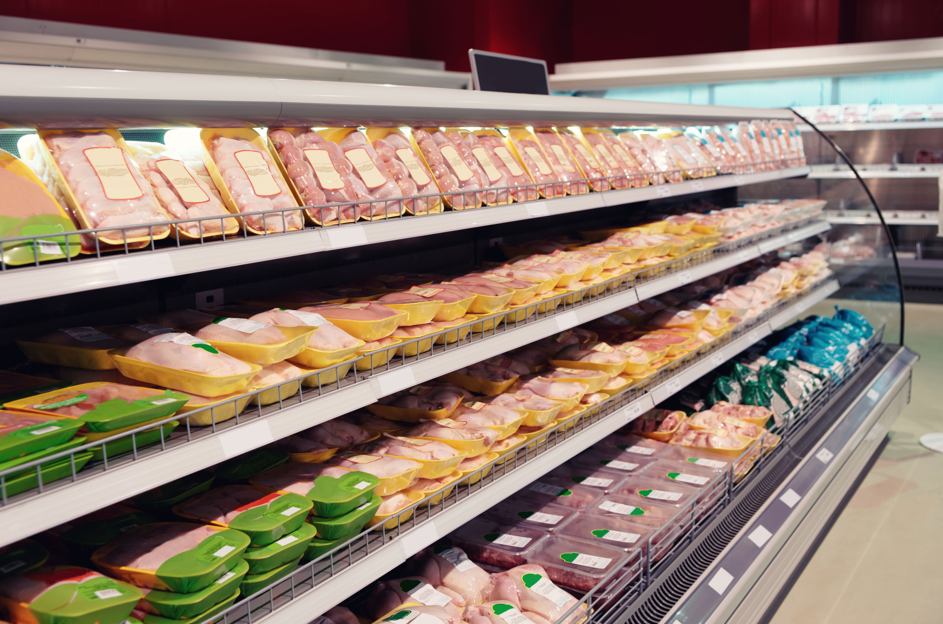 Various packaged poultry products on display in a cooler at a grocery store.