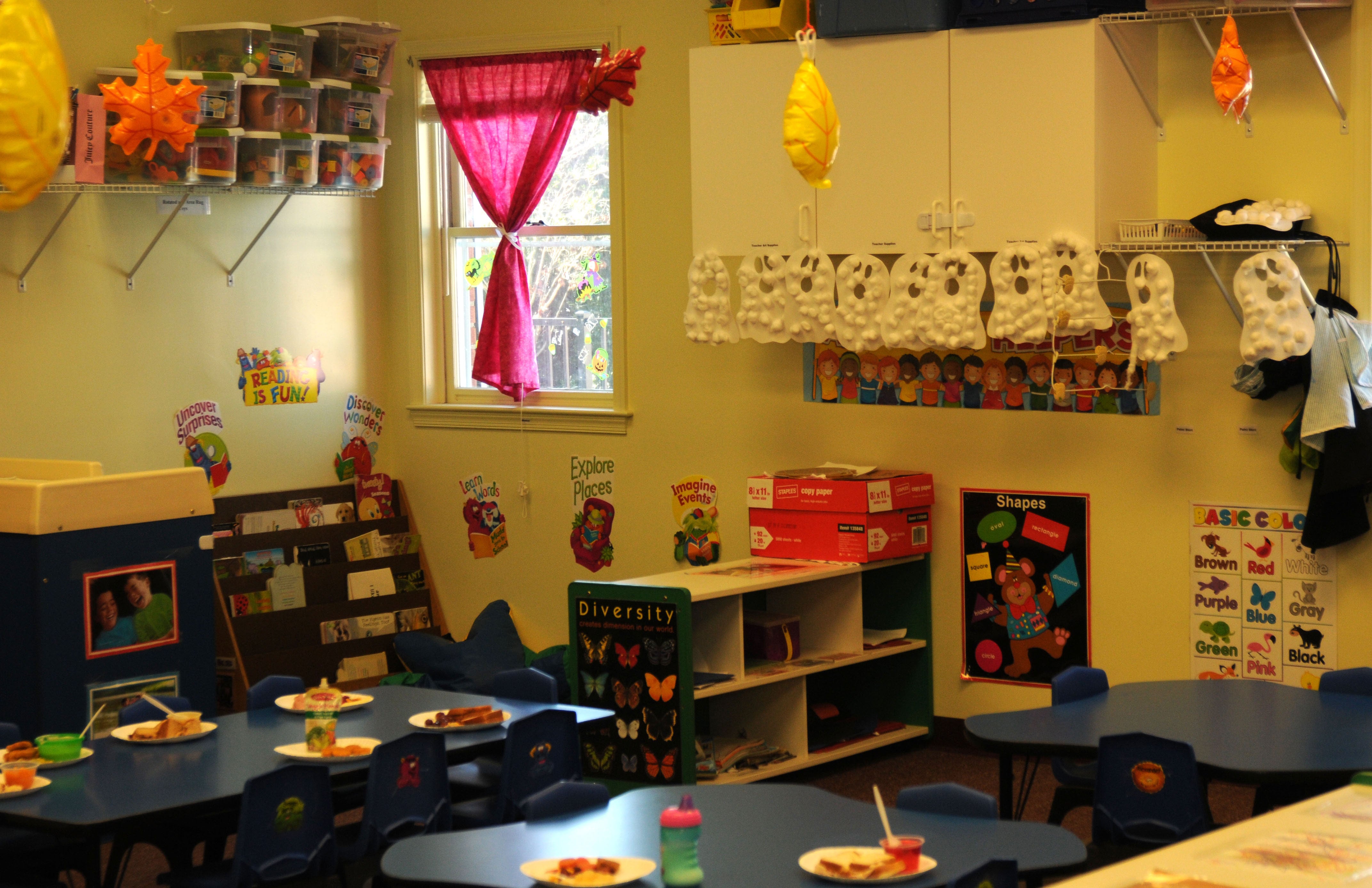 Lunch room in a daycare facility with plates set on the tables and fall decorations in the background.