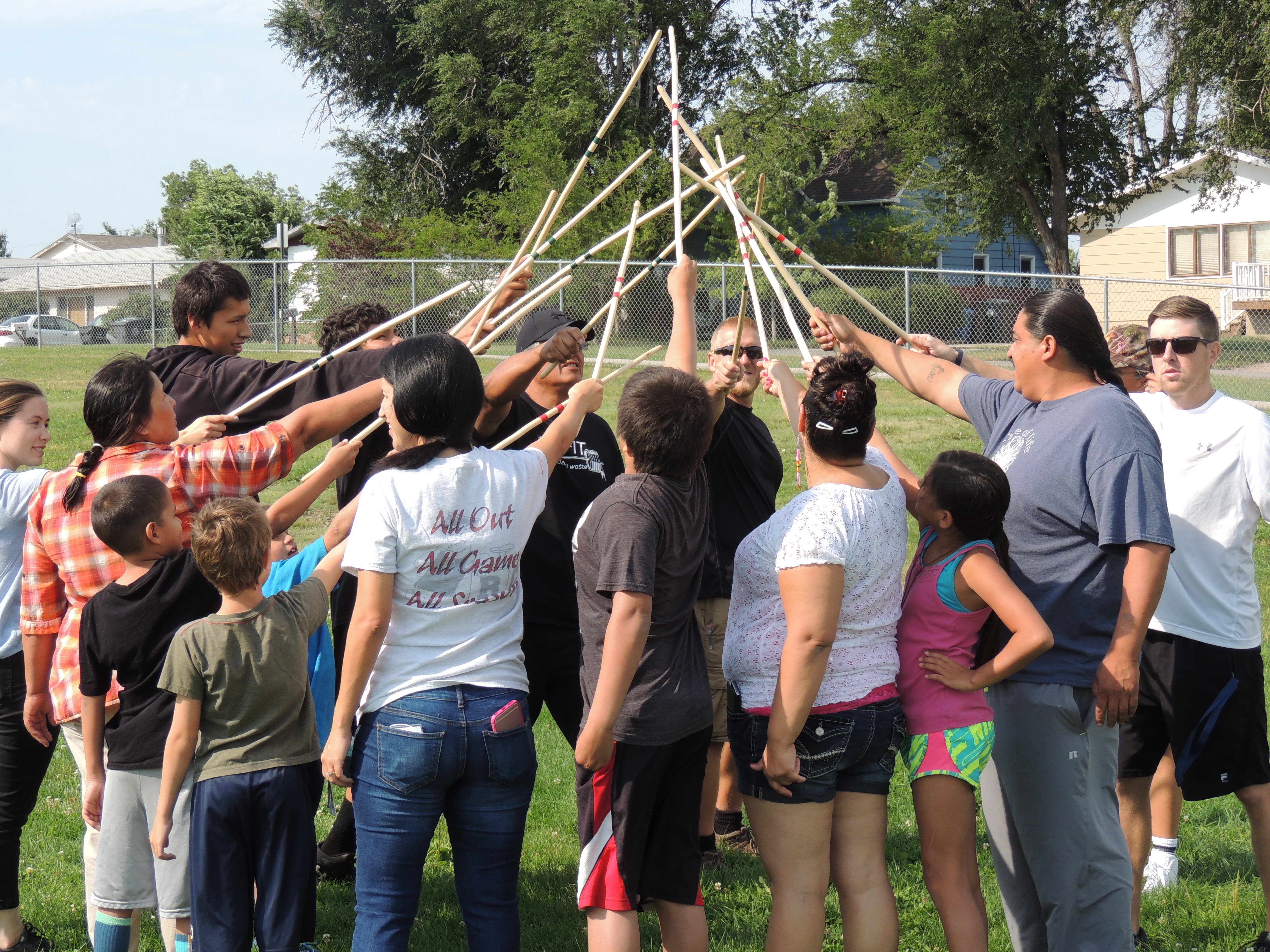 Group of adults and children playing doubleball game in a field