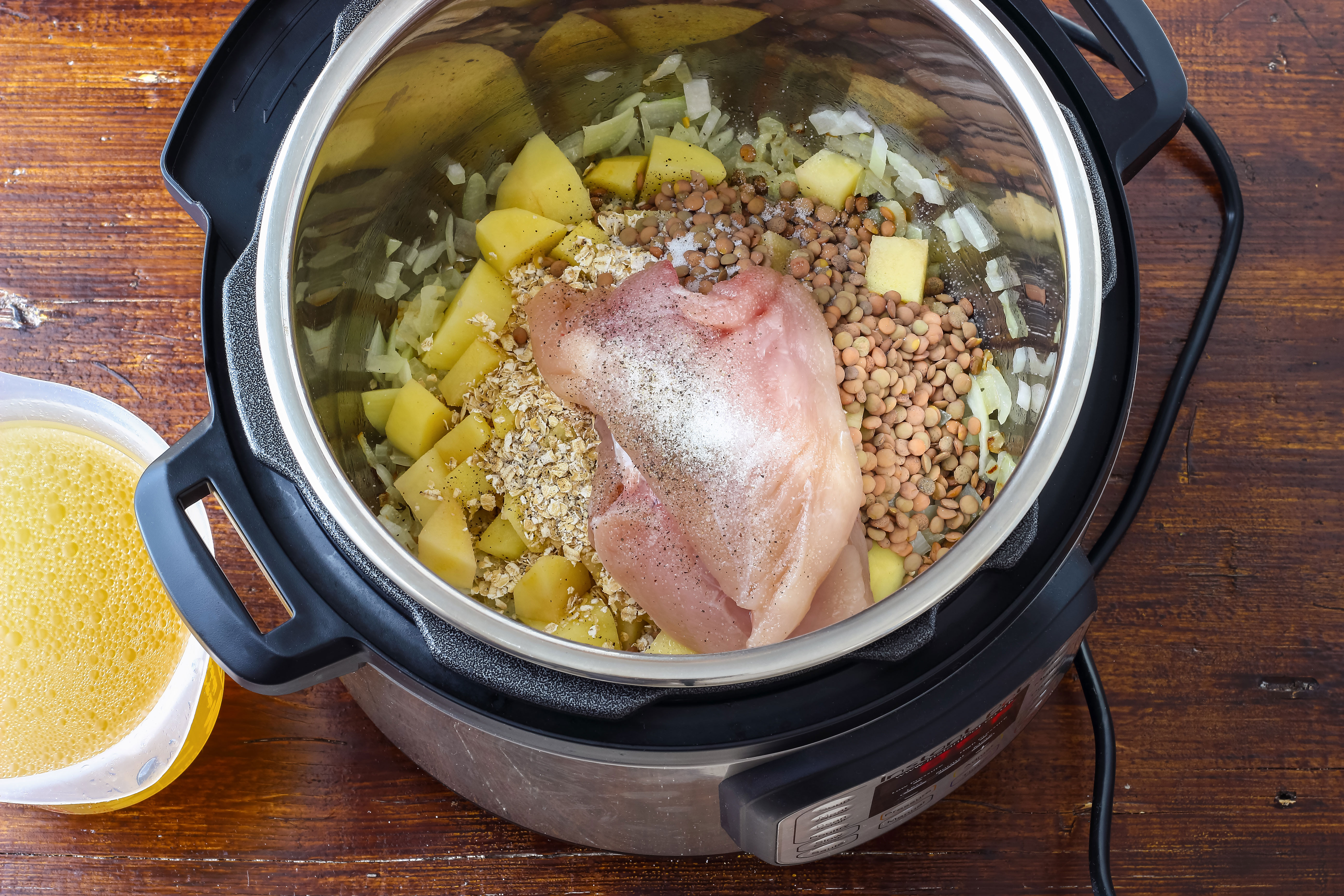 An instant pot pressure cooker with chicken, butter, vegetables, and seasoning inside.