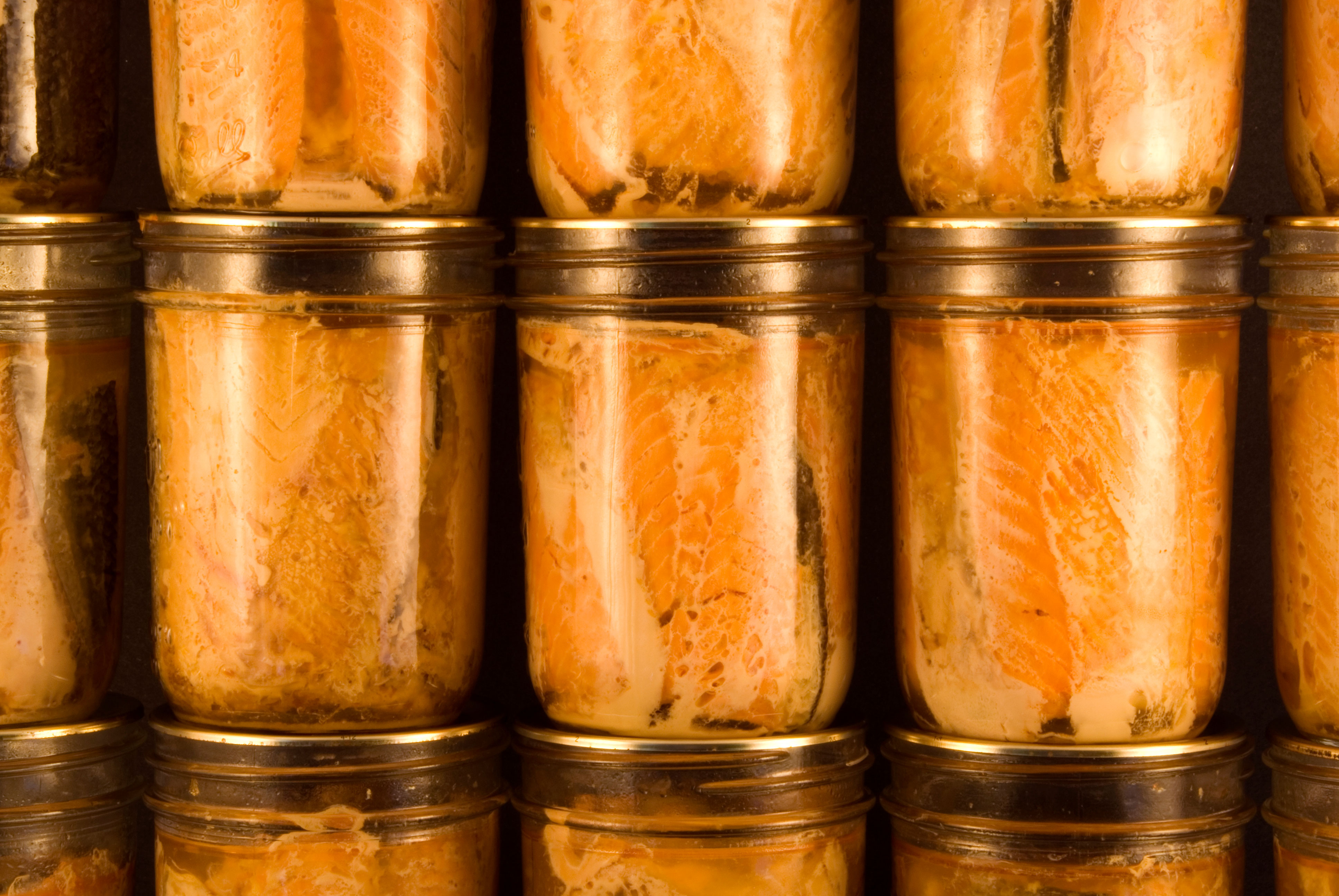 Several jars of canned salmon filets stacked neatly on top of each other.
