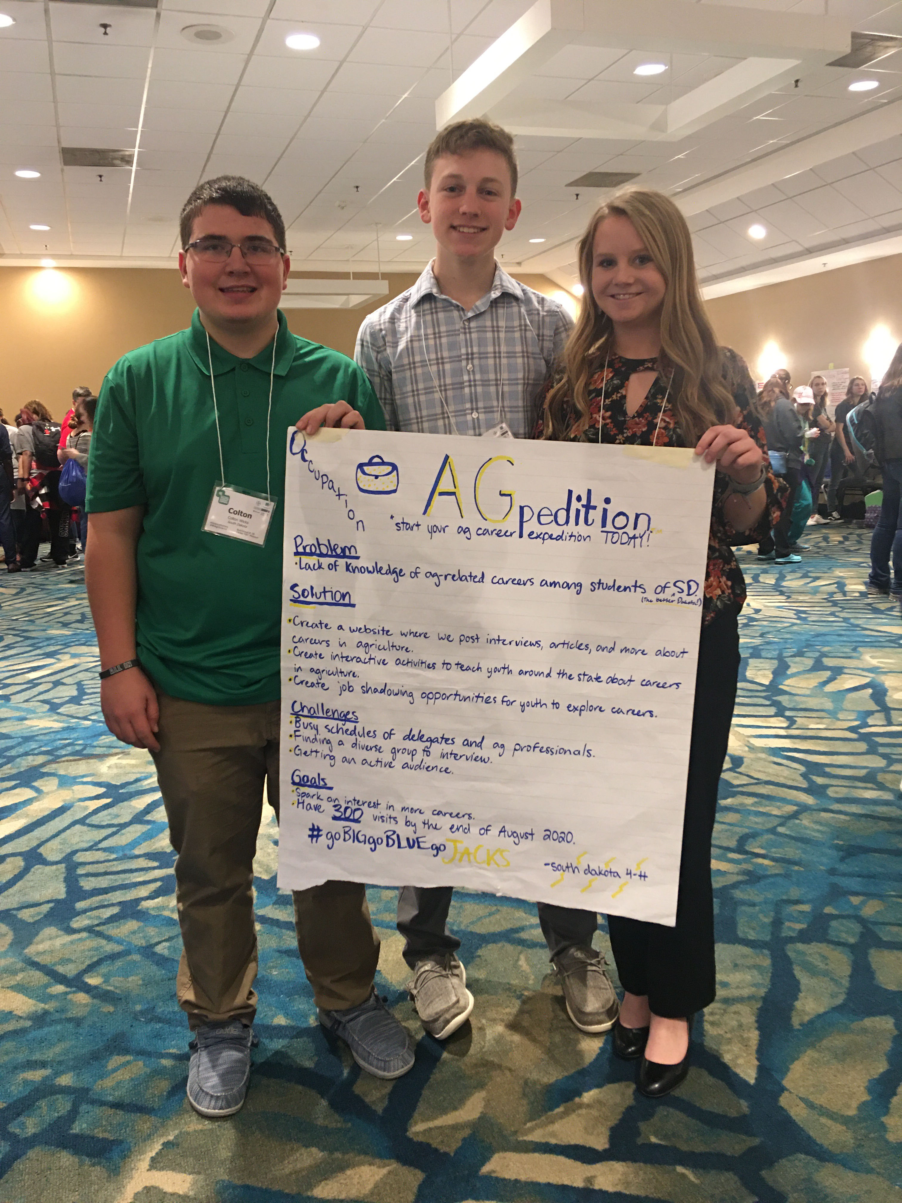 an image of three youth at a conference holding a sign they created