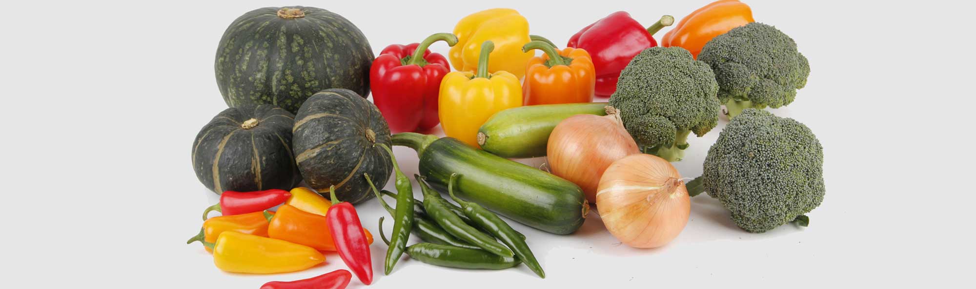 A variety of fresh vegetables displayed on a white countertop.