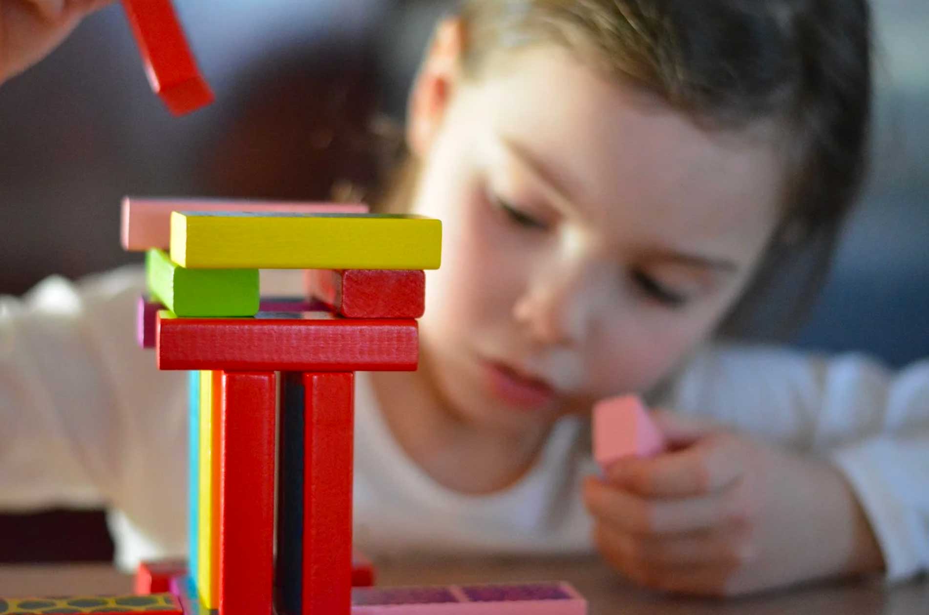 A young girl playing with colored wooden blocks.