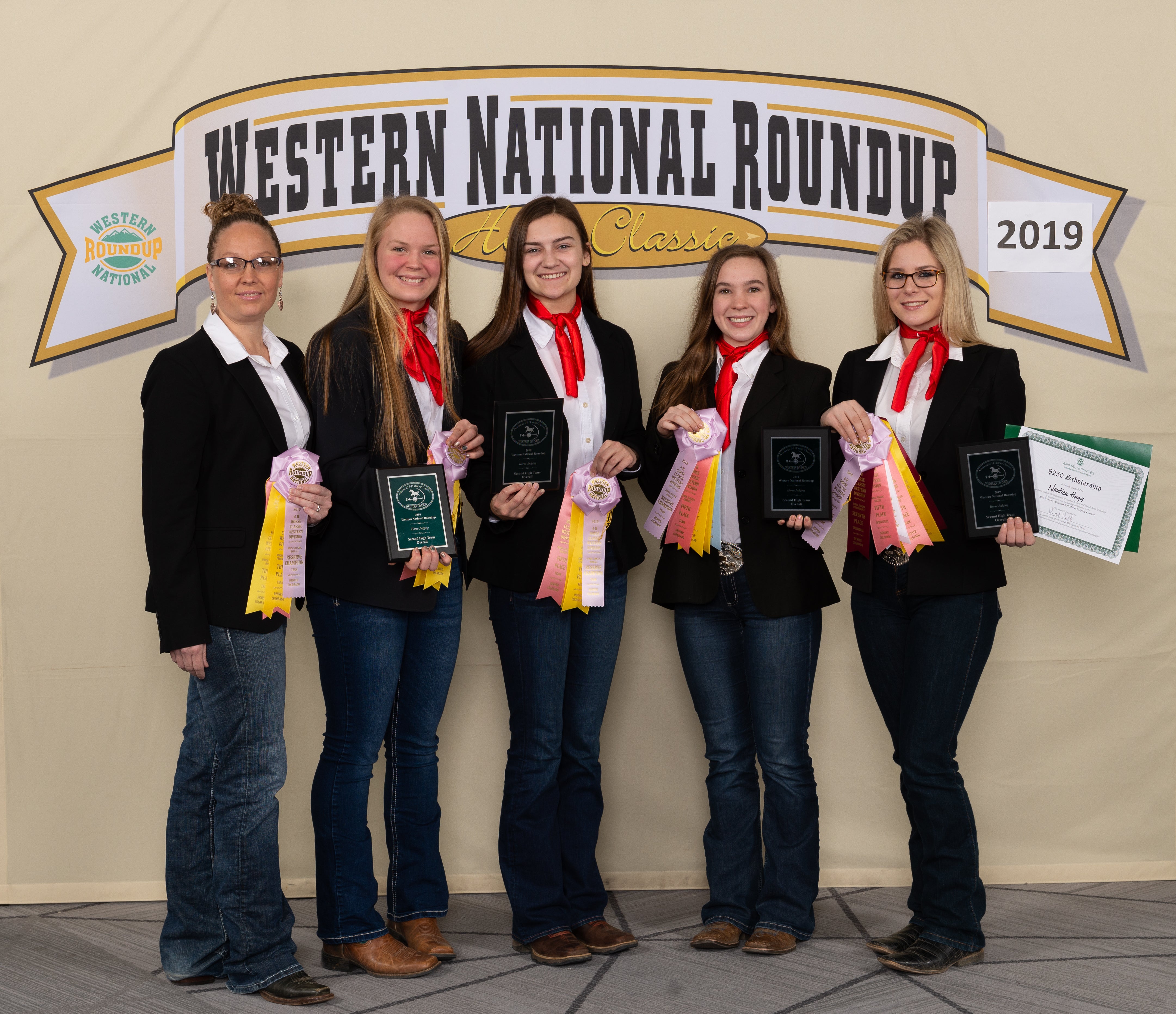 4 young women and their coach standing in front of a sign