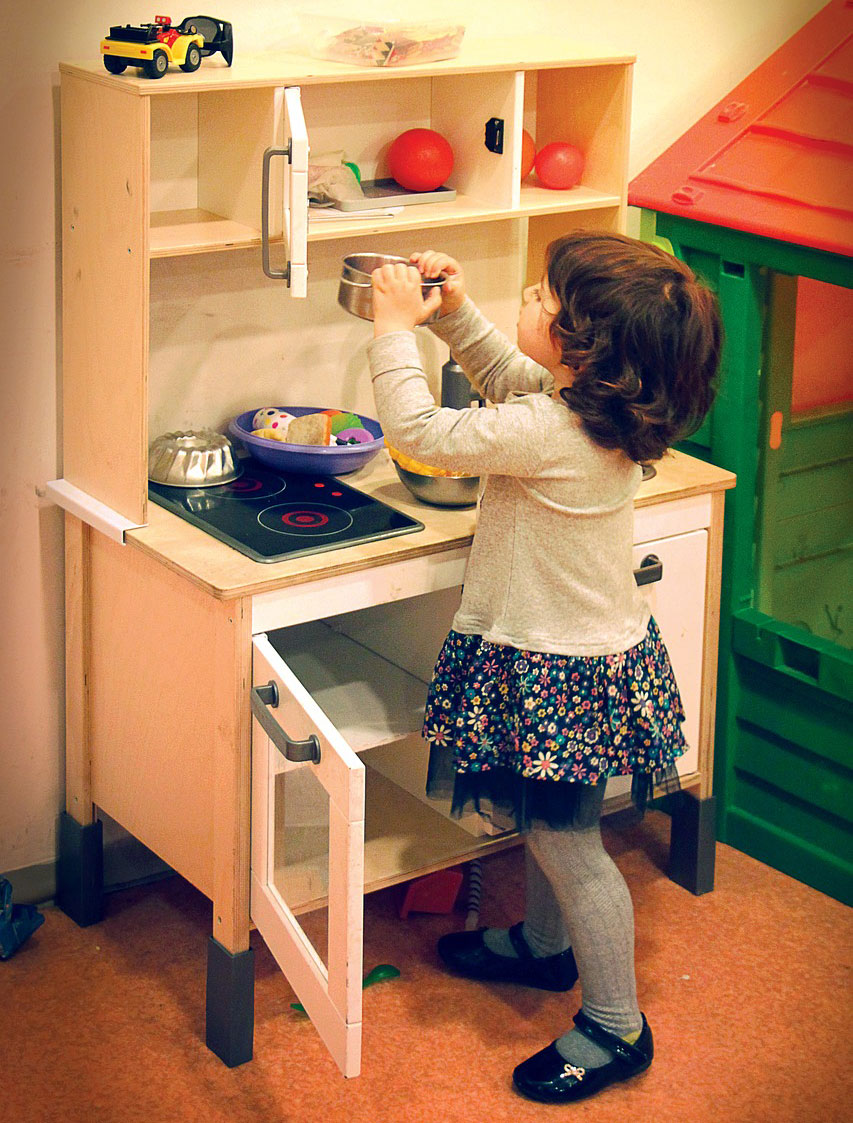 Young girl pretending to cook in a children's play kitchen.