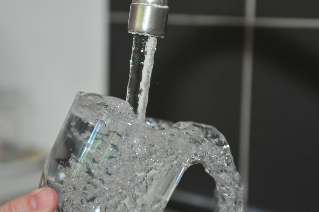 A glass of water being filled from a kitchen sink tap.