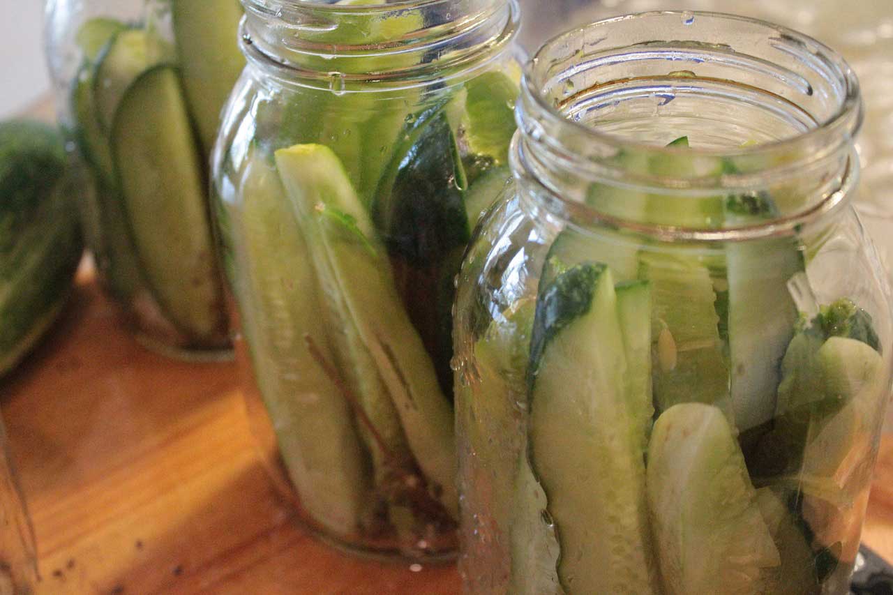 Three canning jars filled with cucumber slices.