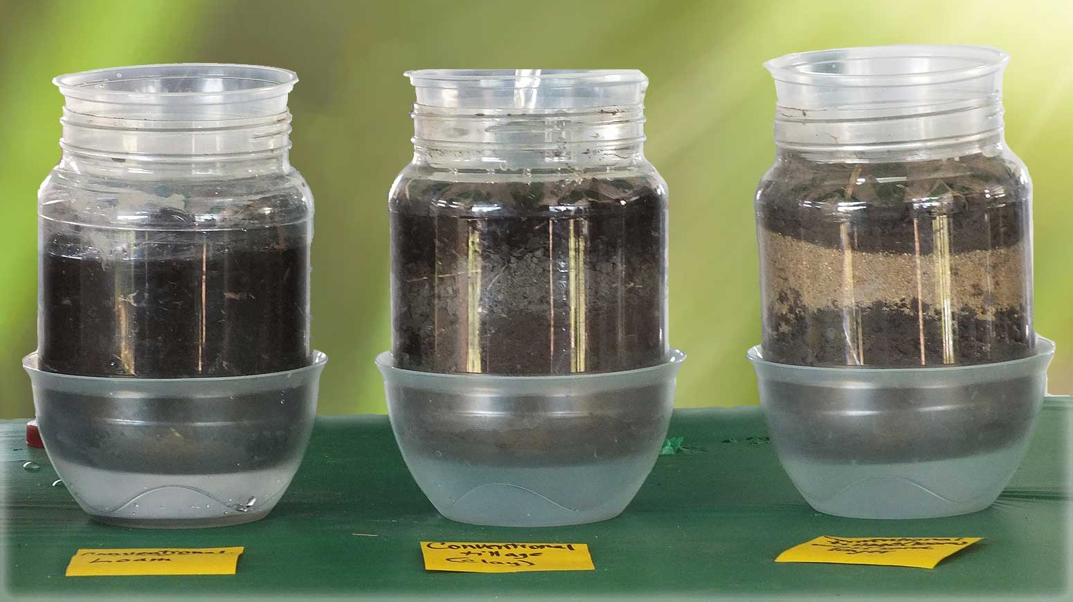 Three clear jars revealing layers of soil and compost.