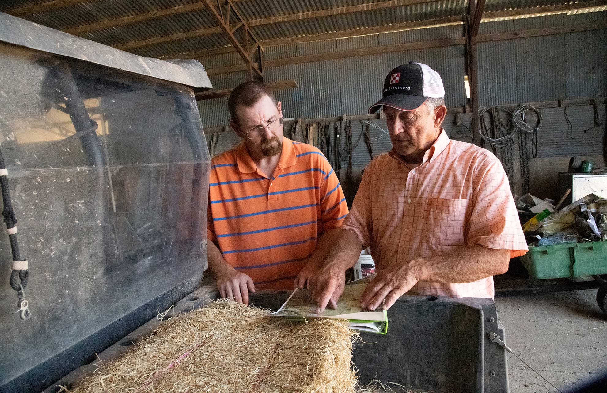 A rancher and RMA agent reviewing insurance paperwork beside a off-road vehicle.