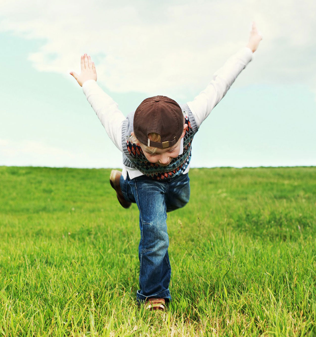 Boy posing on one leg with arms raised to the sky.