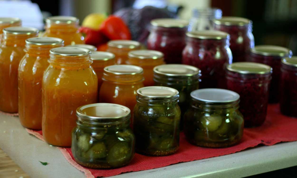 Canned fruit, vegetables and preserves arranged on a tabletop.