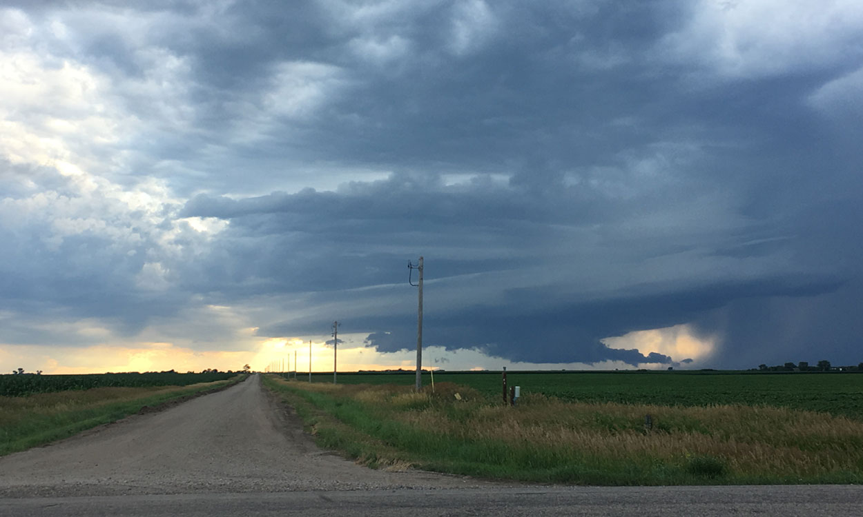 Country road with a thunderstorm approaching in the distance.